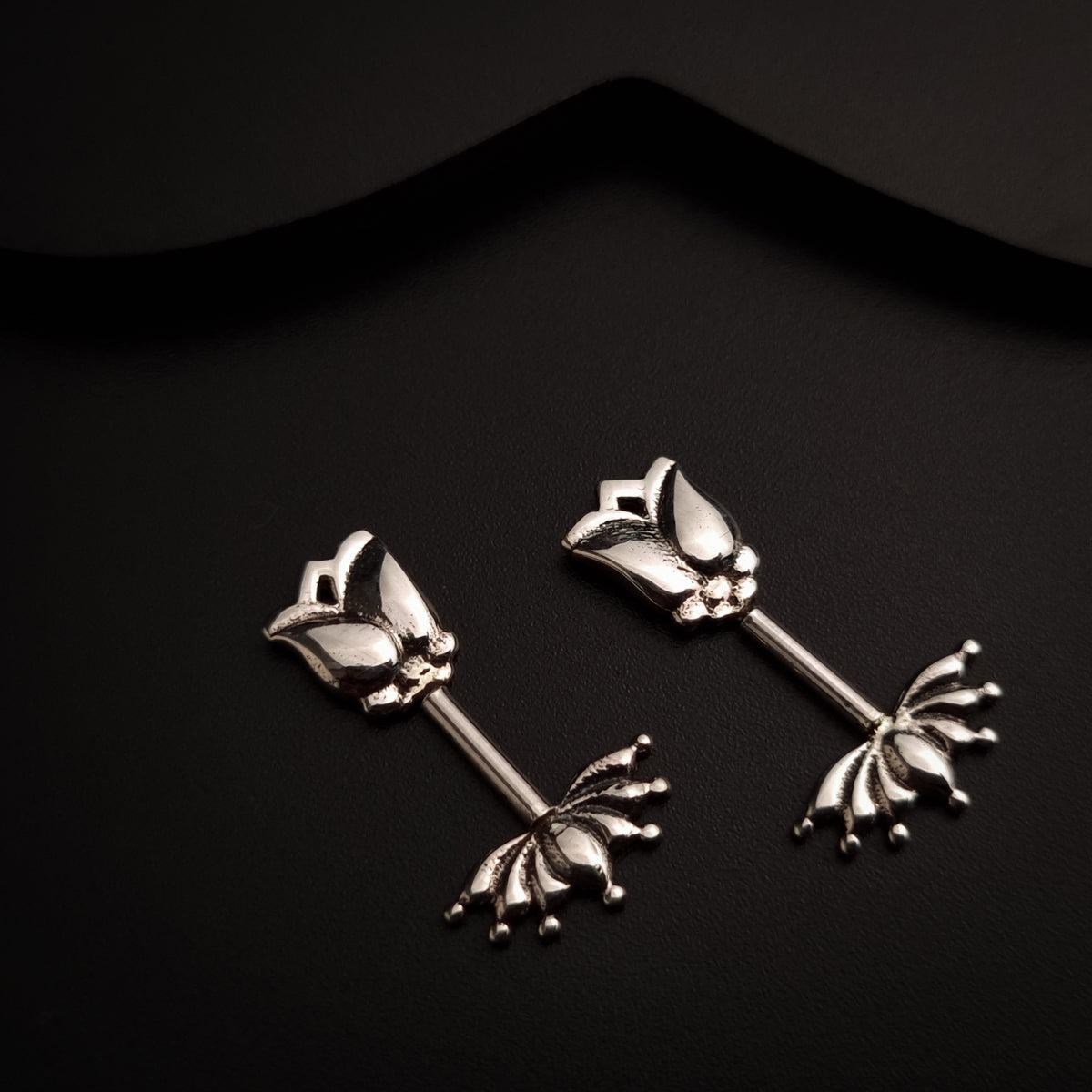 a pair of silver earrings on a black background