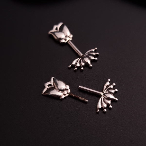 a pair of silver earrings on a black surface