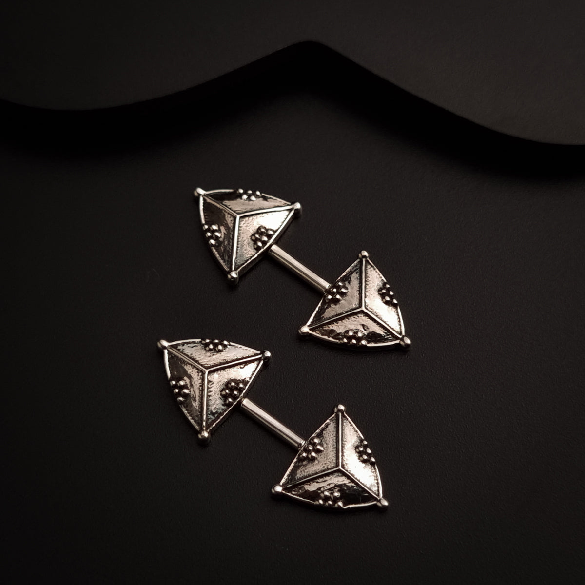 a pair of triangle shaped studs on a black background