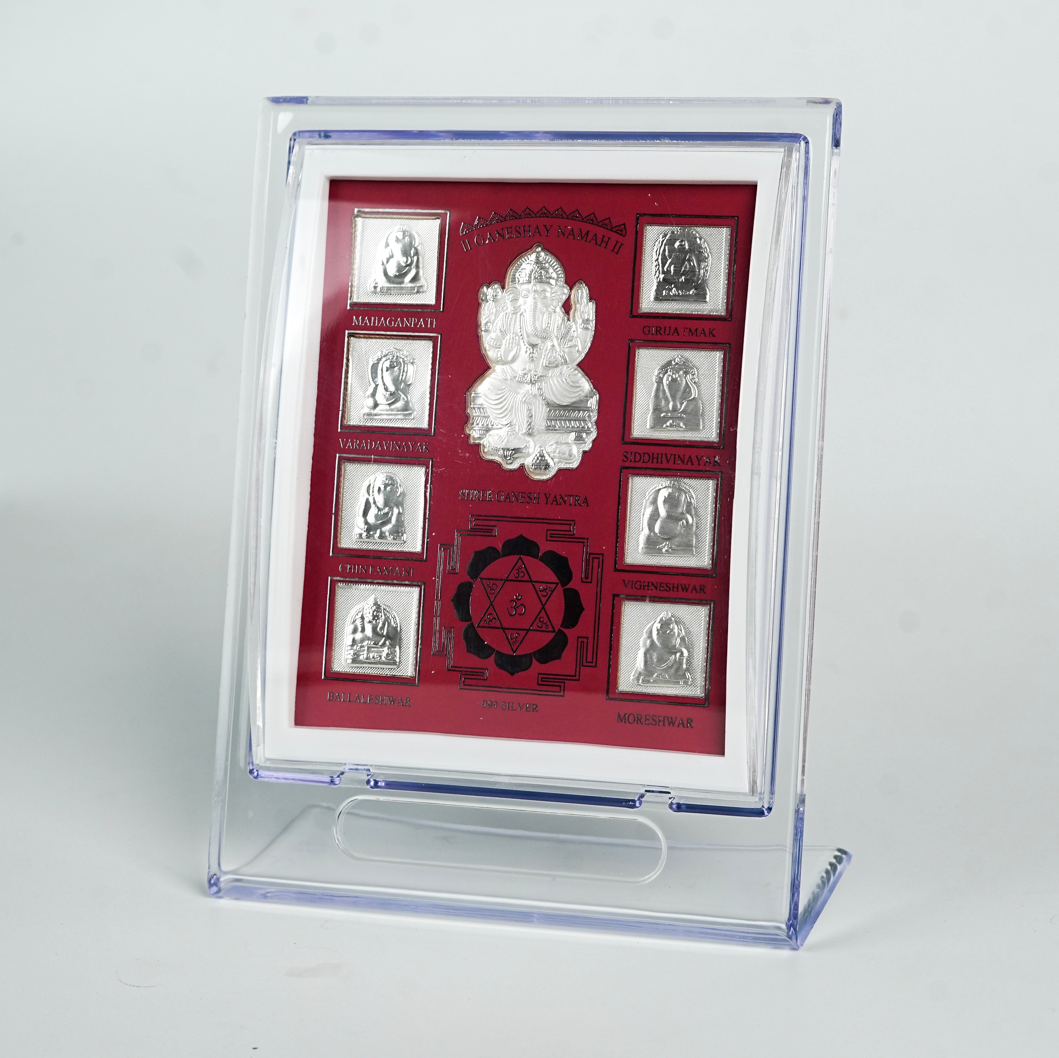 Close-up of silver Ganesh Yantra frame with red background and detailed silver images