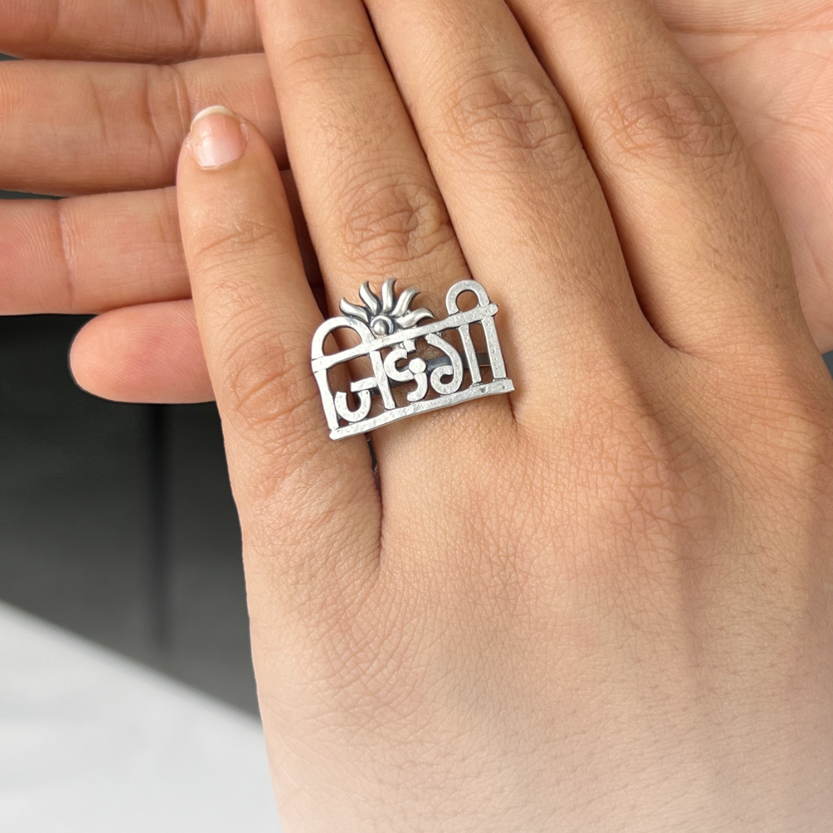 a woman's hand holding a silver ring with a flower on it