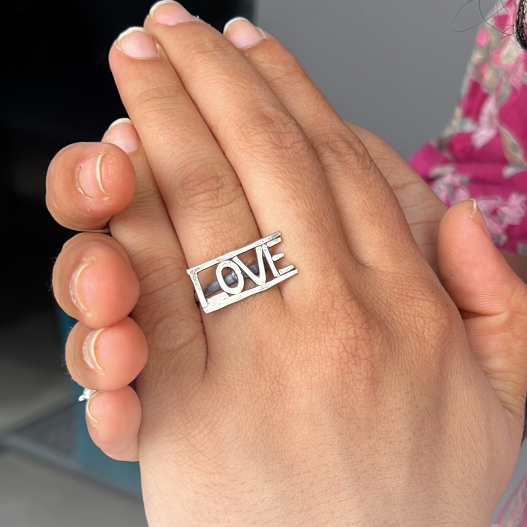 a woman's hand holding a ring with the word love on it