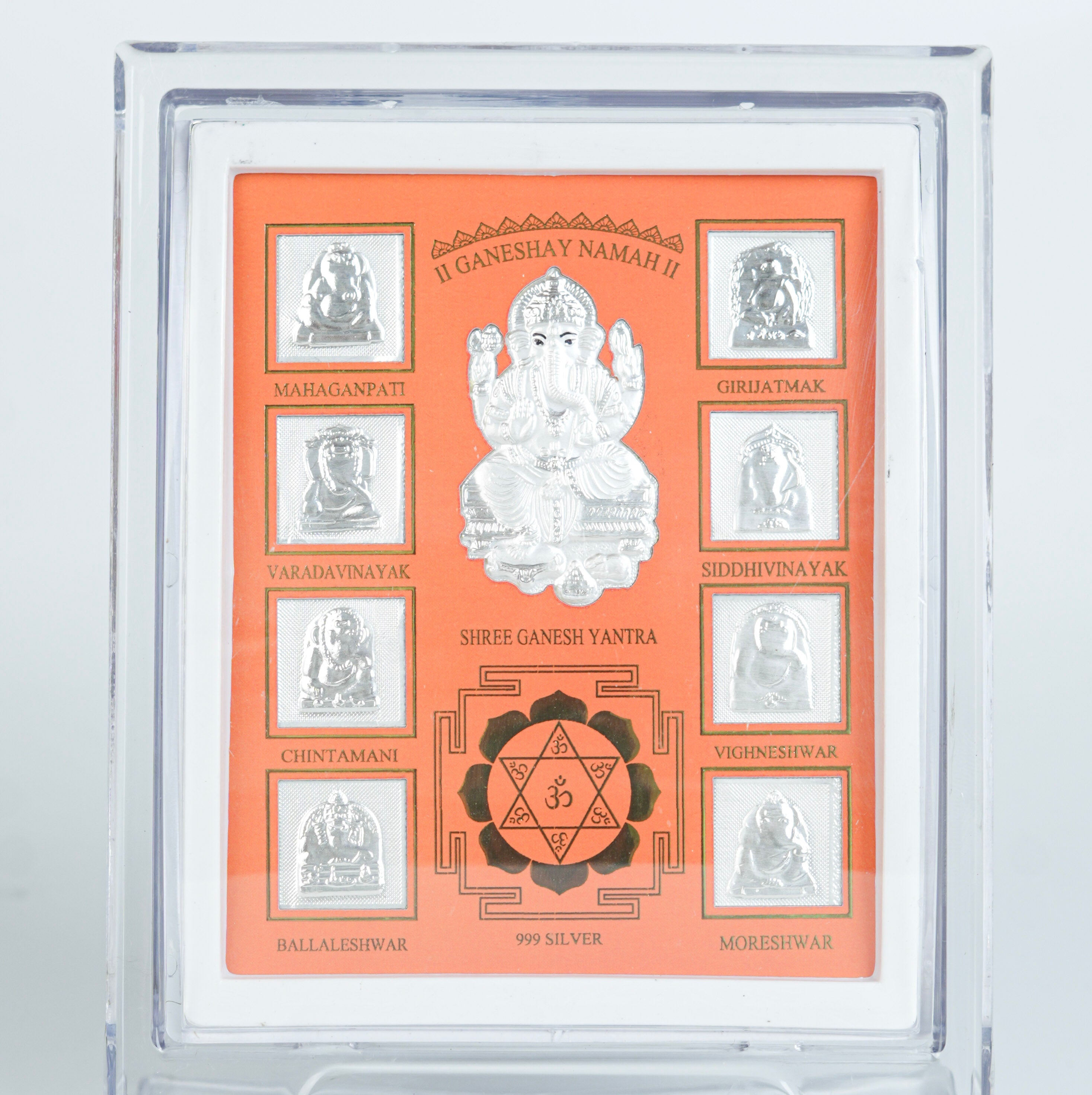 Close-up of silver Ganesh Yantra frame with orange background