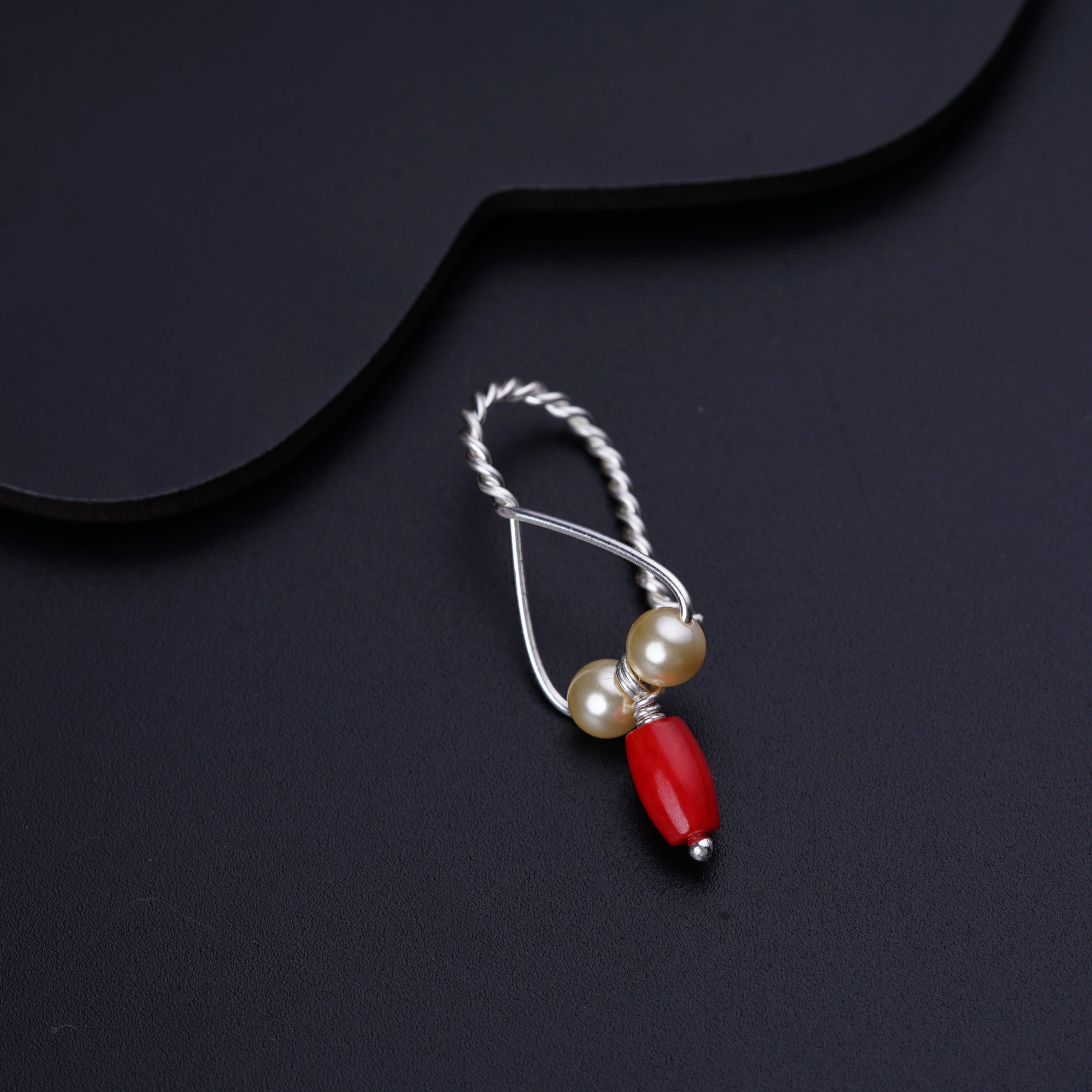a red and white beaded necklace on a black surface