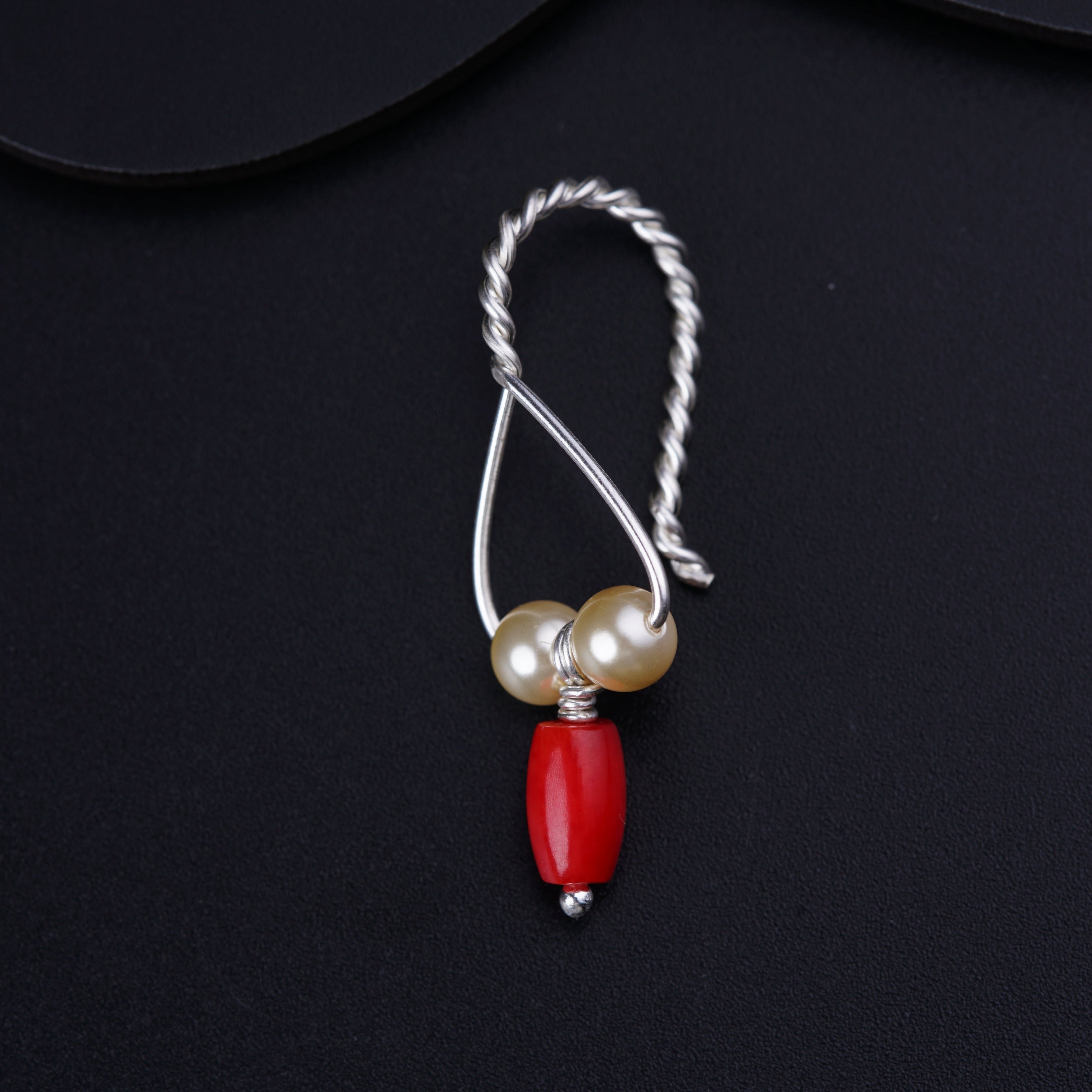 a necklace with a red bead and two pearls