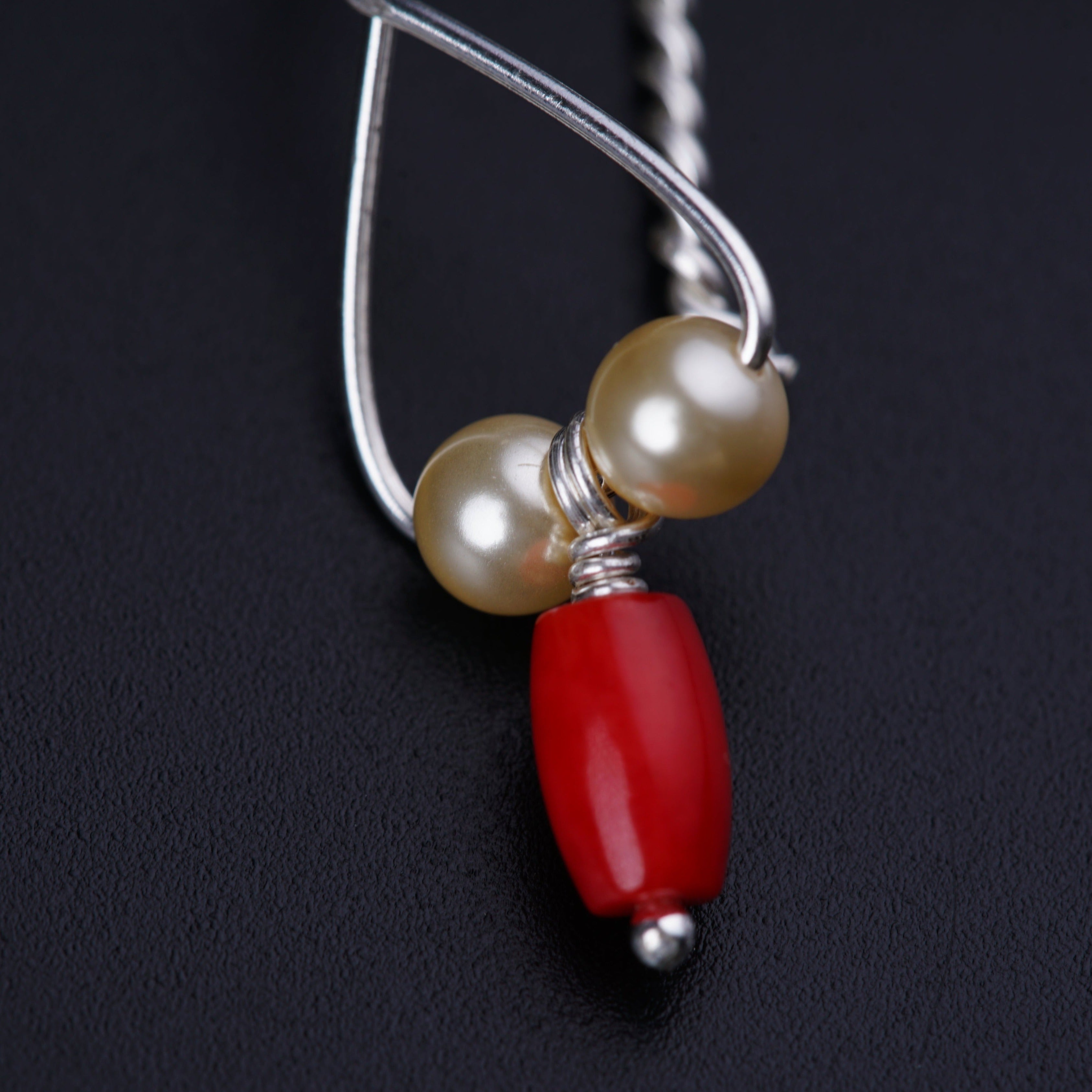 a close up of a necklace with a red bead