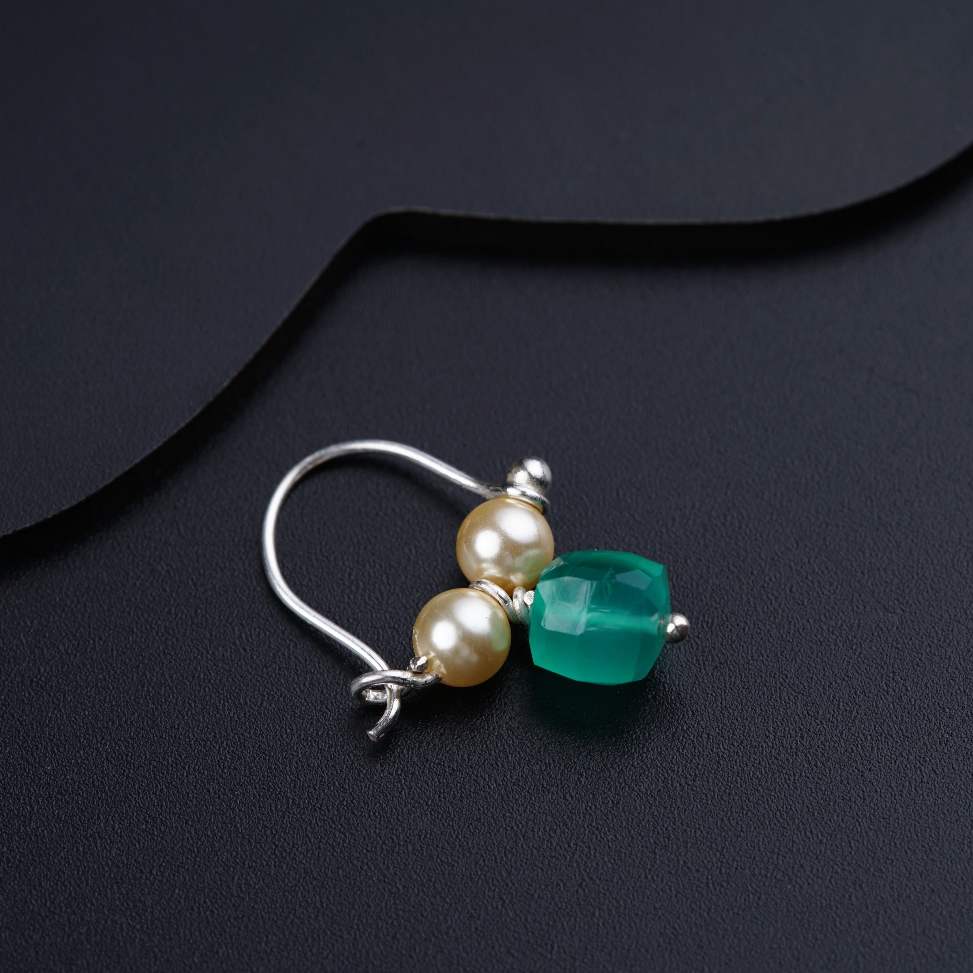 a pair of earrings with pearls and a green bead