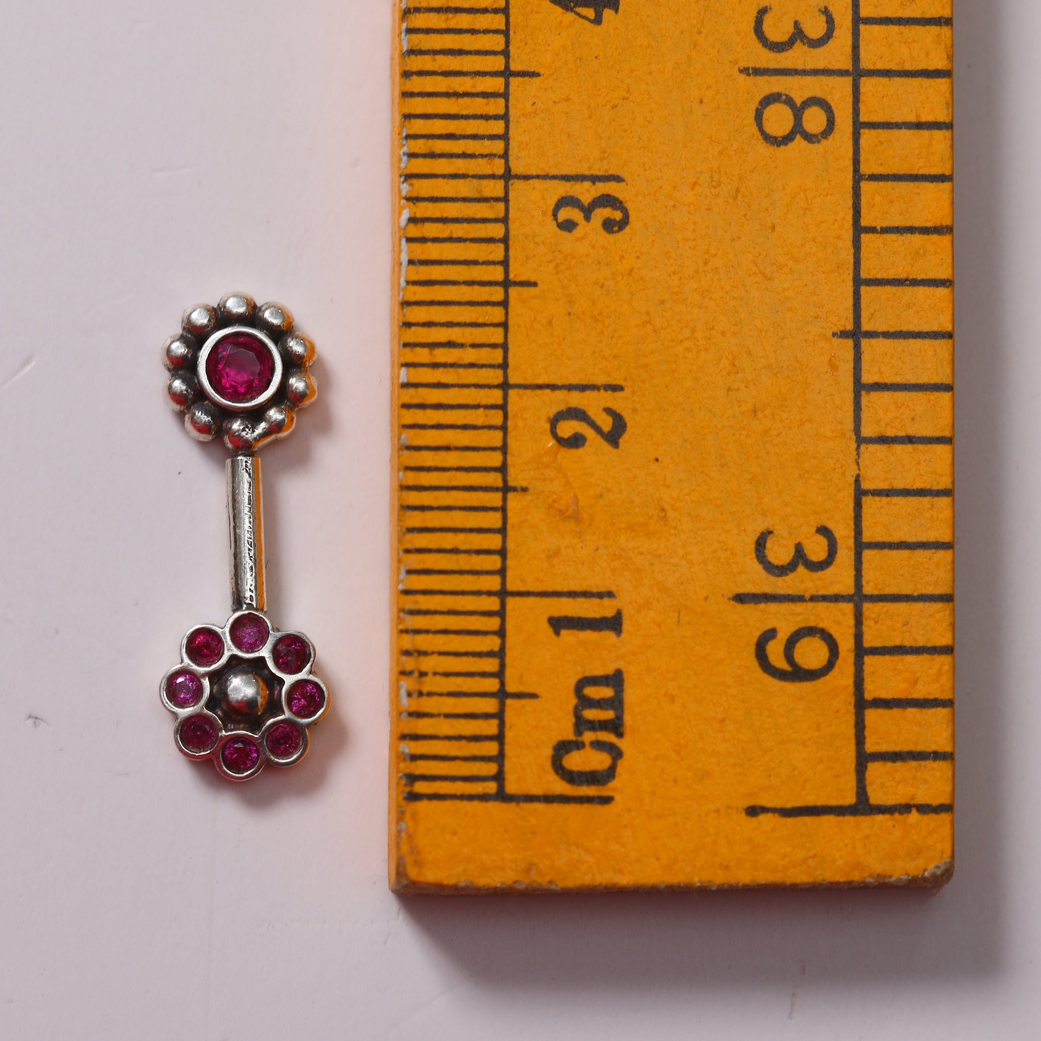 a pair of earrings sitting next to a ruler