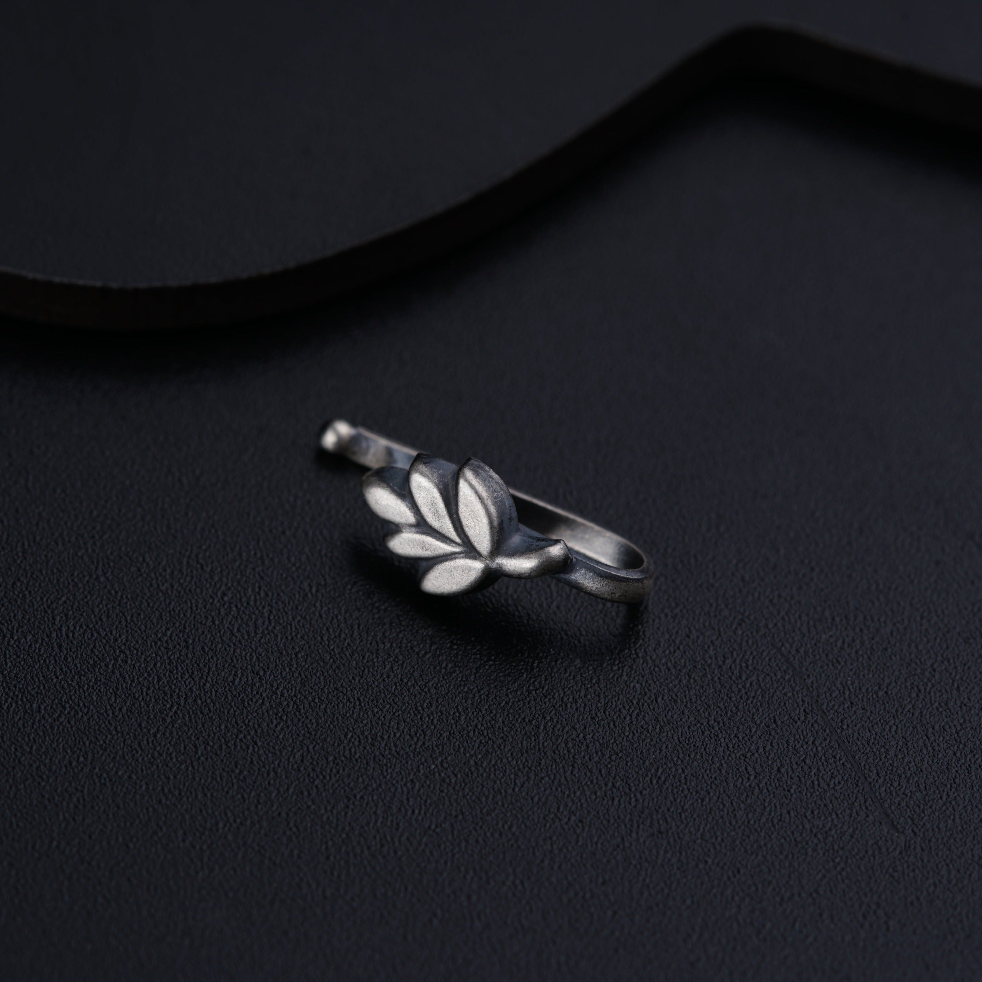 a silver ring with leaves on it sitting on a black surface