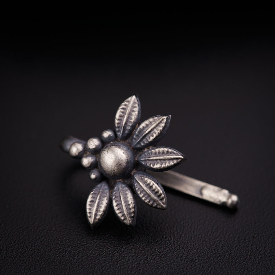 a silver flower shaped hair clip on a black surface
