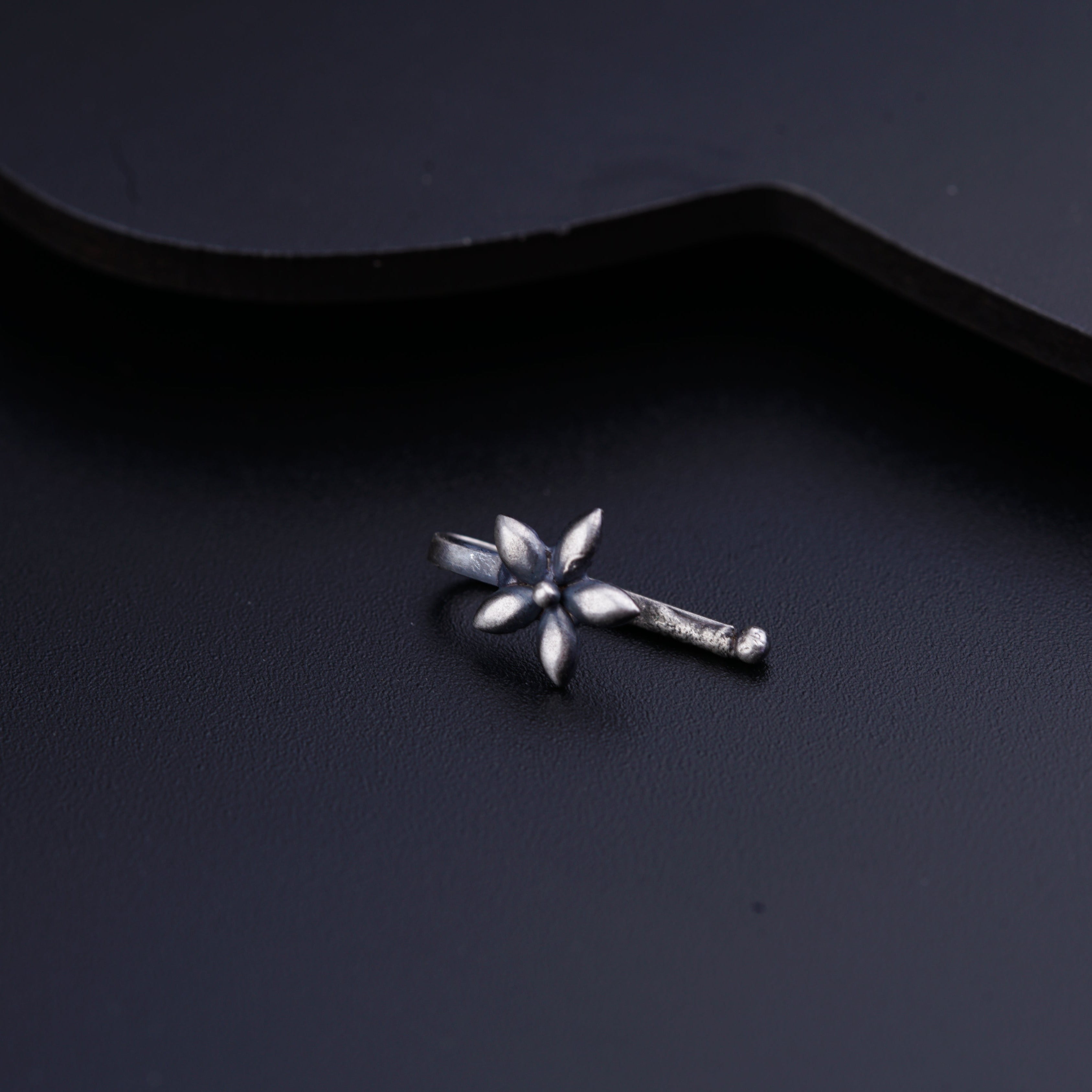 a small metal flower on a black surface