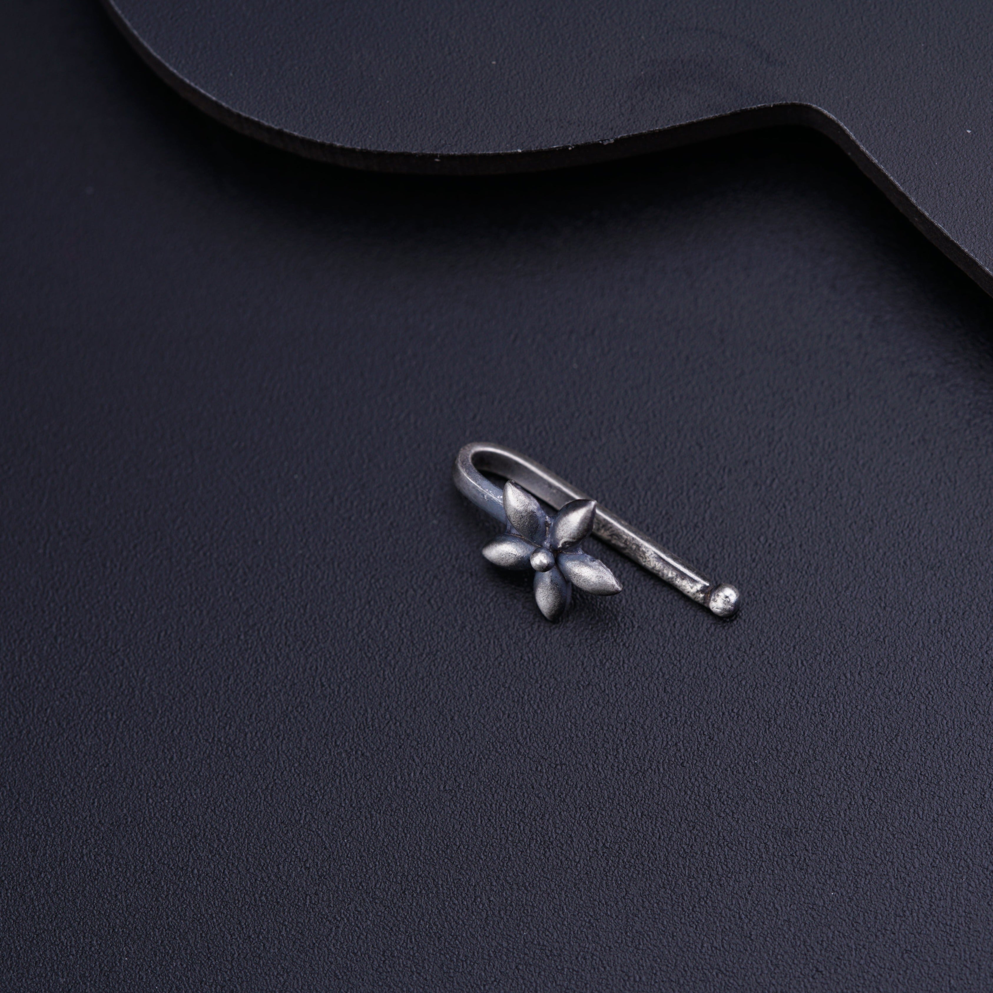 a guitar pick with a small silver flower on it
