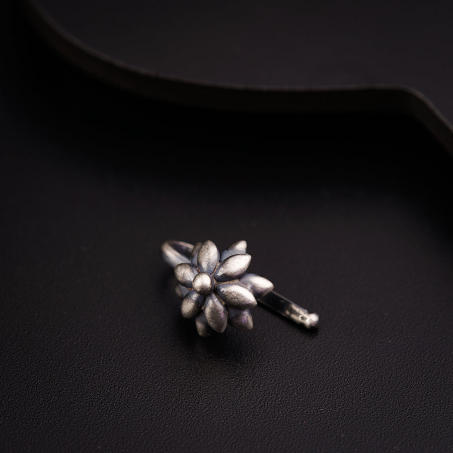 a silver flower brooch sitting on top of a black surface