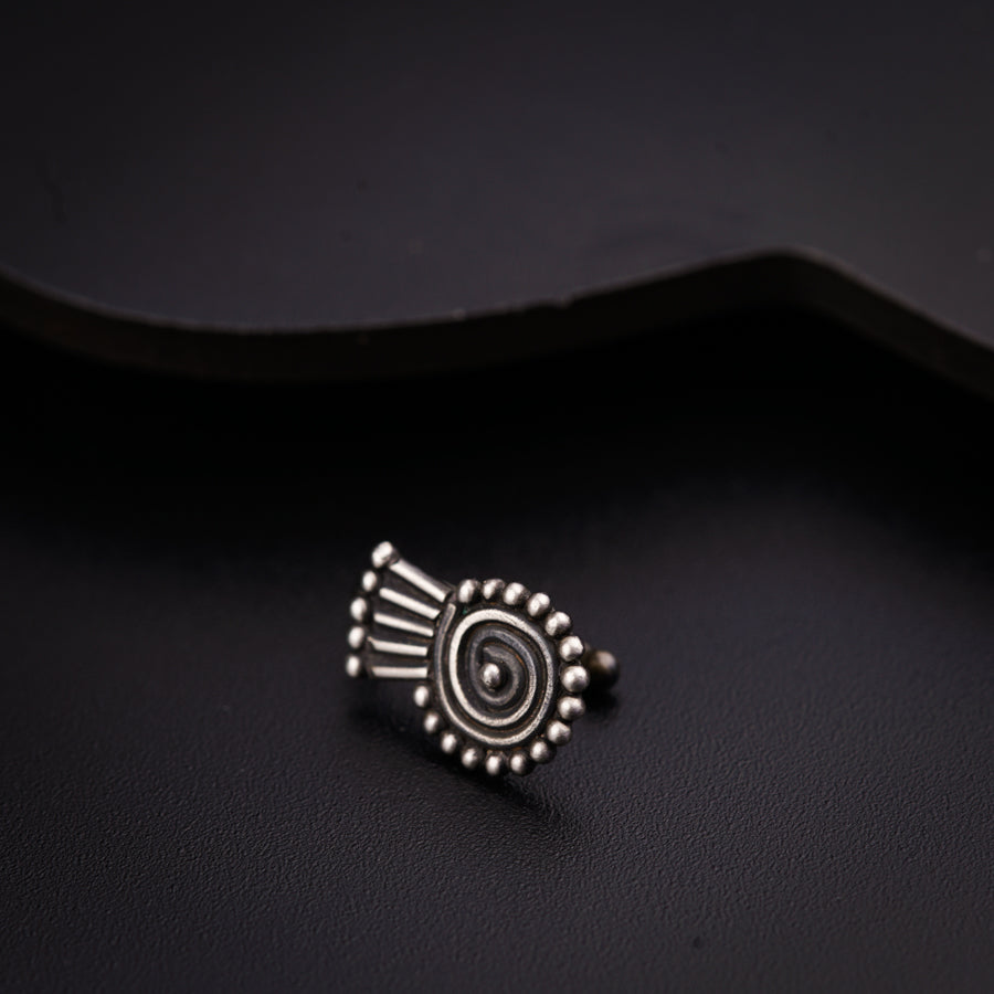 a small silver ring sitting on top of a black surface