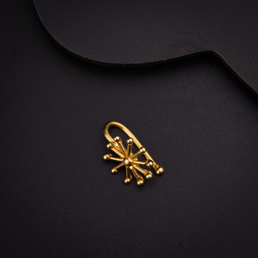 a pair of gold earrings on a black surface