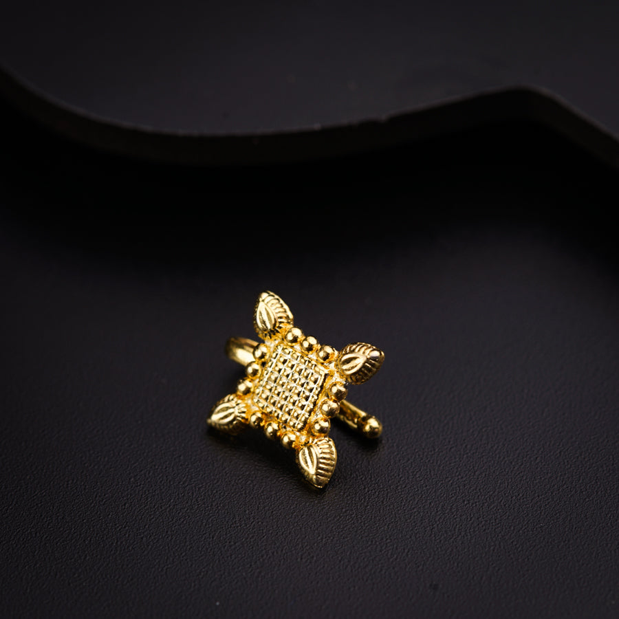 a close up of a gold brooch on a black surface