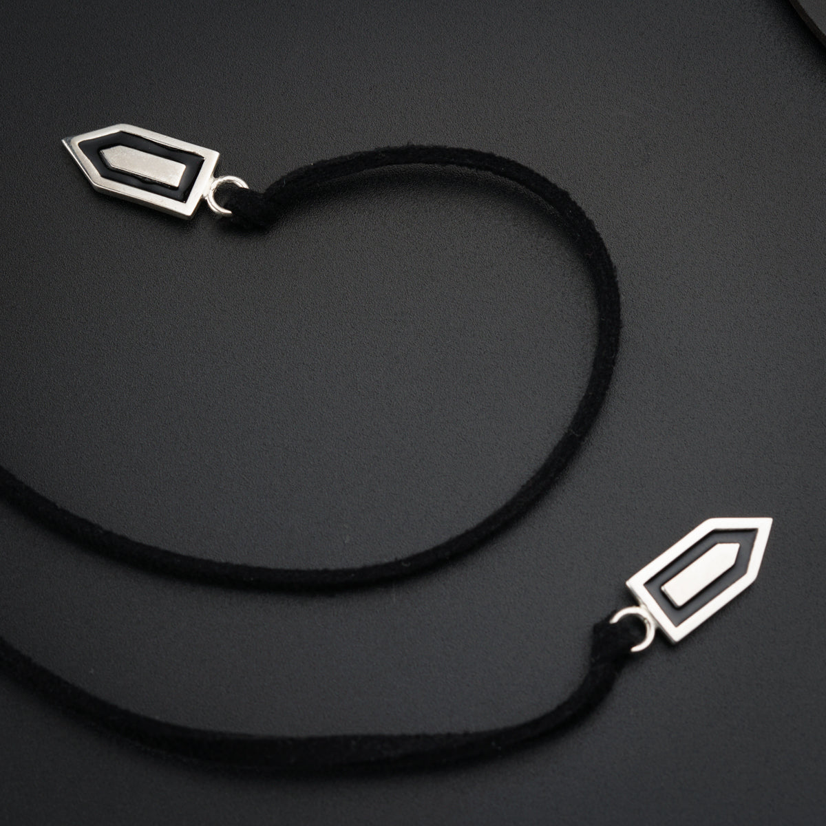 a black cord with two silver pendants on it