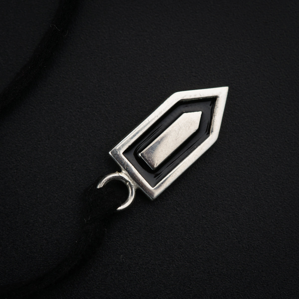 a black and silver pendant on a black background
