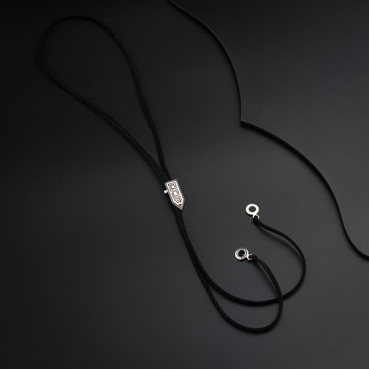 a black lanyard with two silver beads on a black background