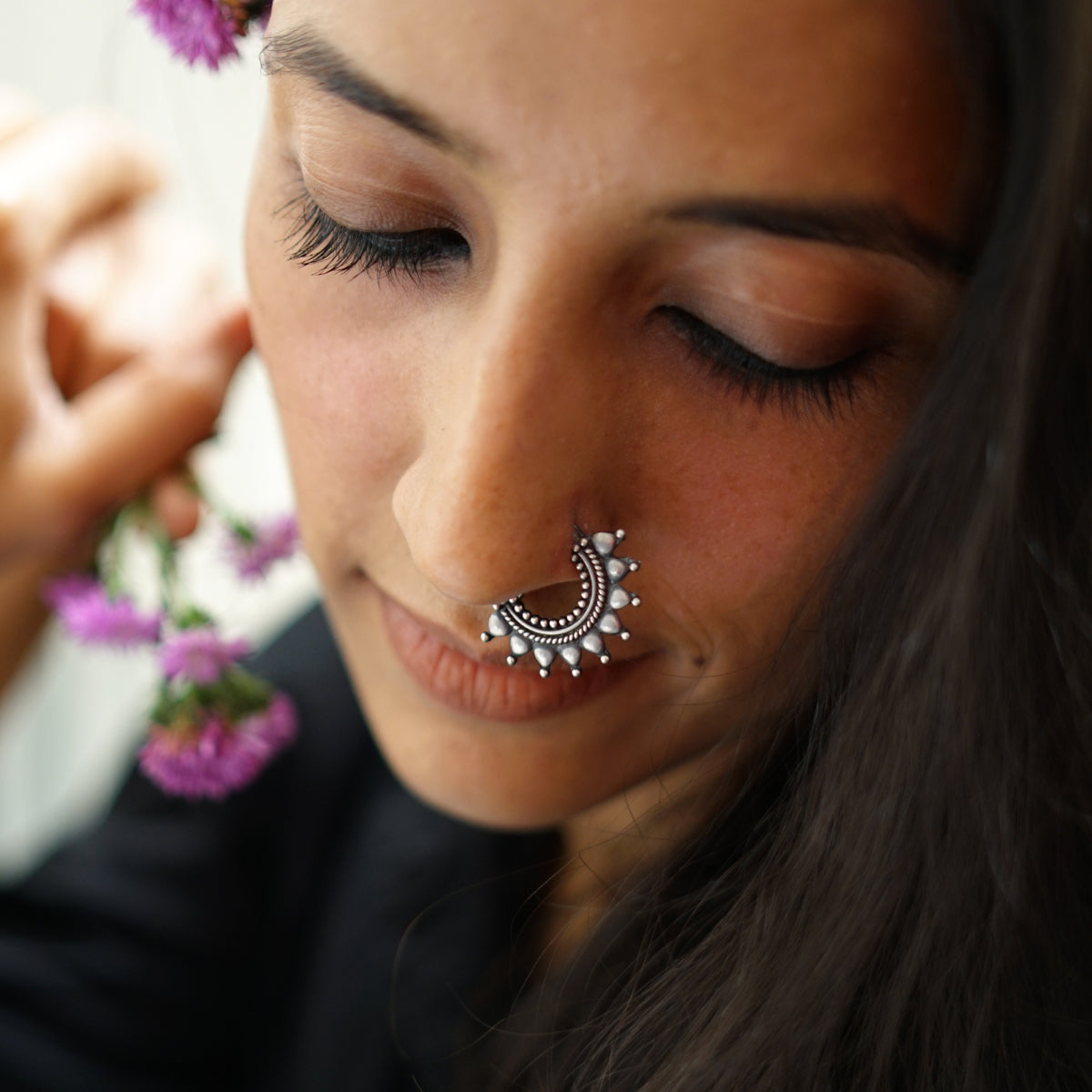 a woman wearing a nose ring with a flower in her hair