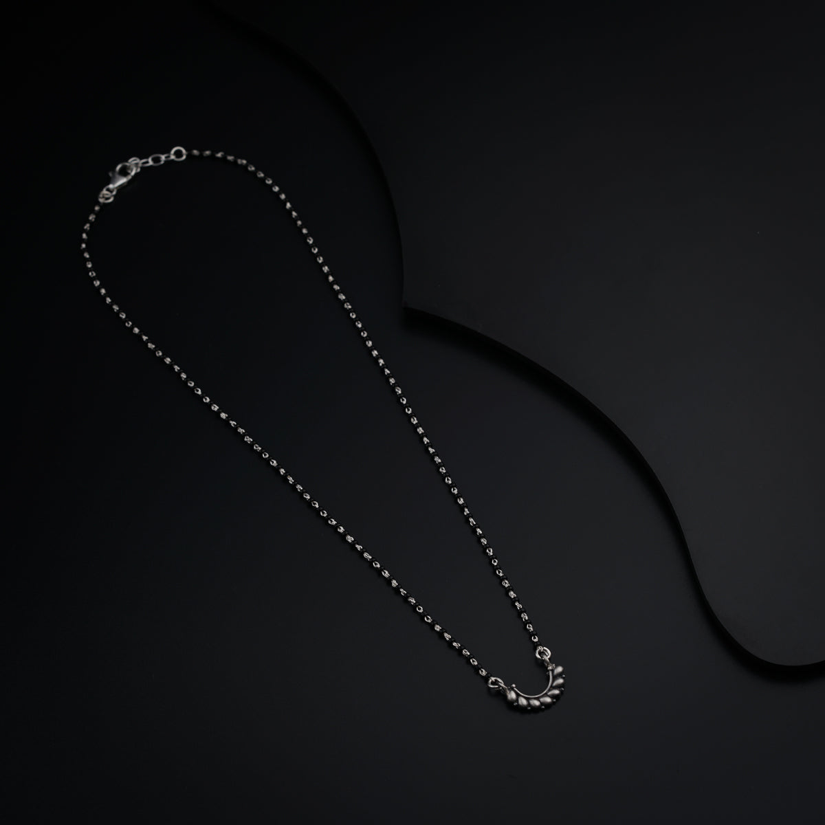 a black background with a silver necklace on it