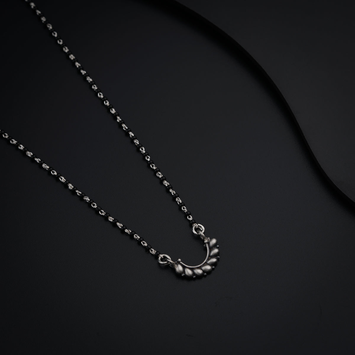 a necklace with a flower on it on a black surface