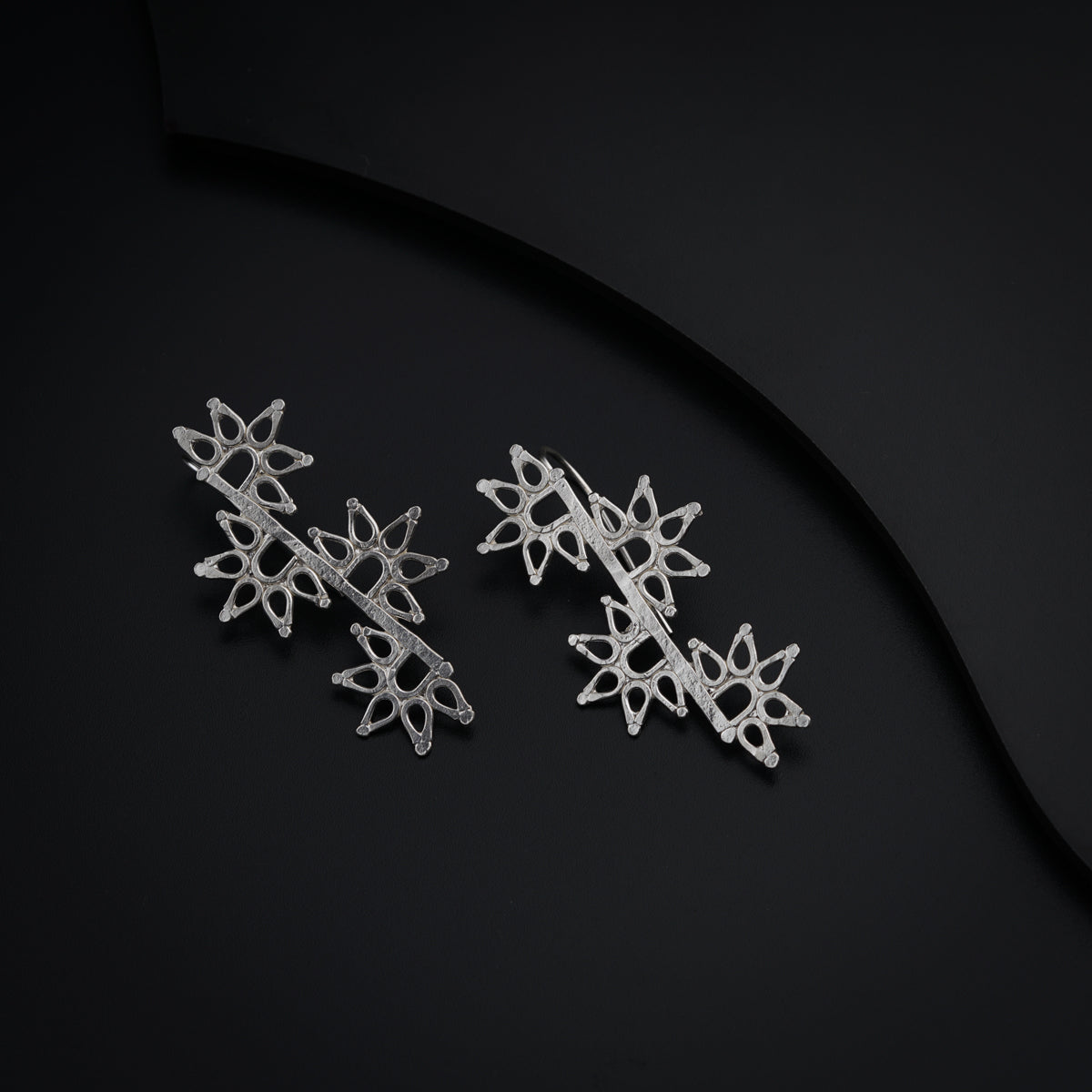 a pair of snowflake earrings on a black surface