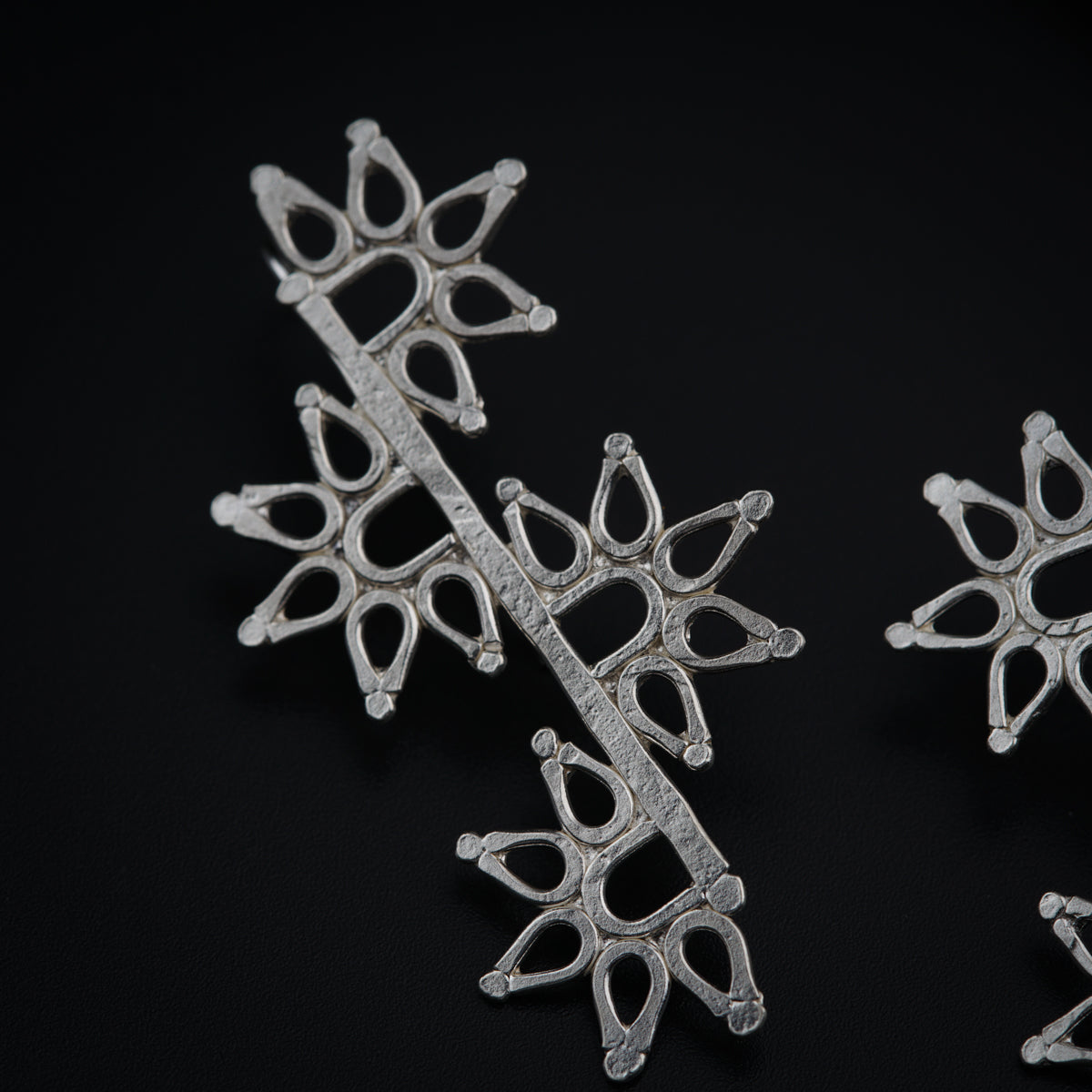 a close up of three silver brooches on a black surface