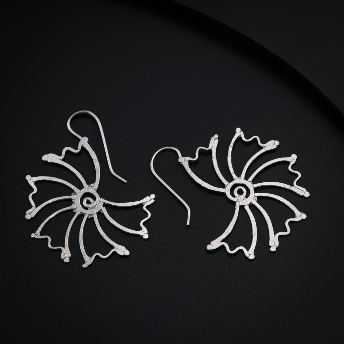 a pair of silver earrings on a black surface