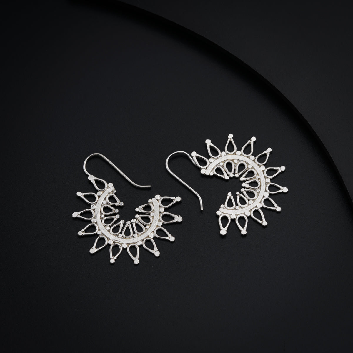 a pair of white earrings sitting on top of a black surface