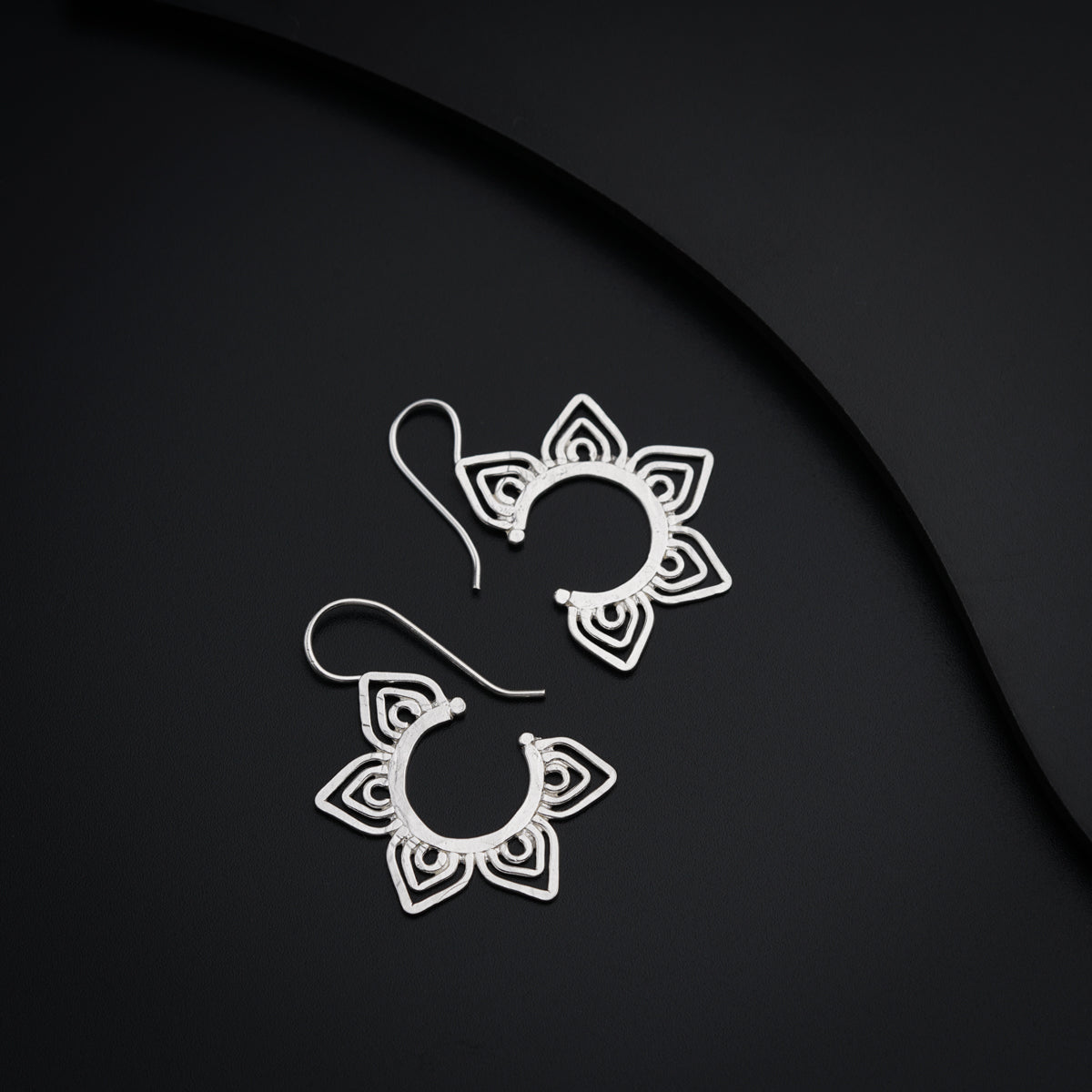 a pair of earrings sitting on top of a black surface