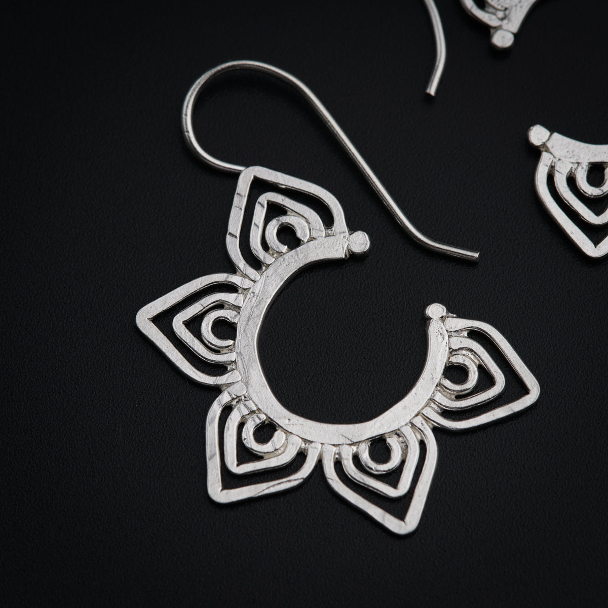 a pair of silver earrings on a black surface