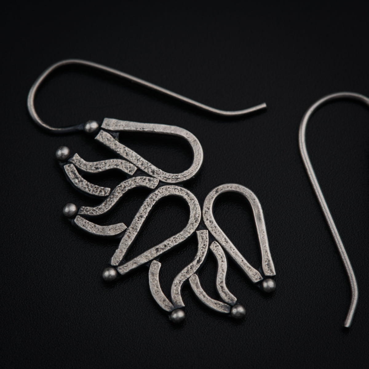 a pair of silver earrings on a black surface