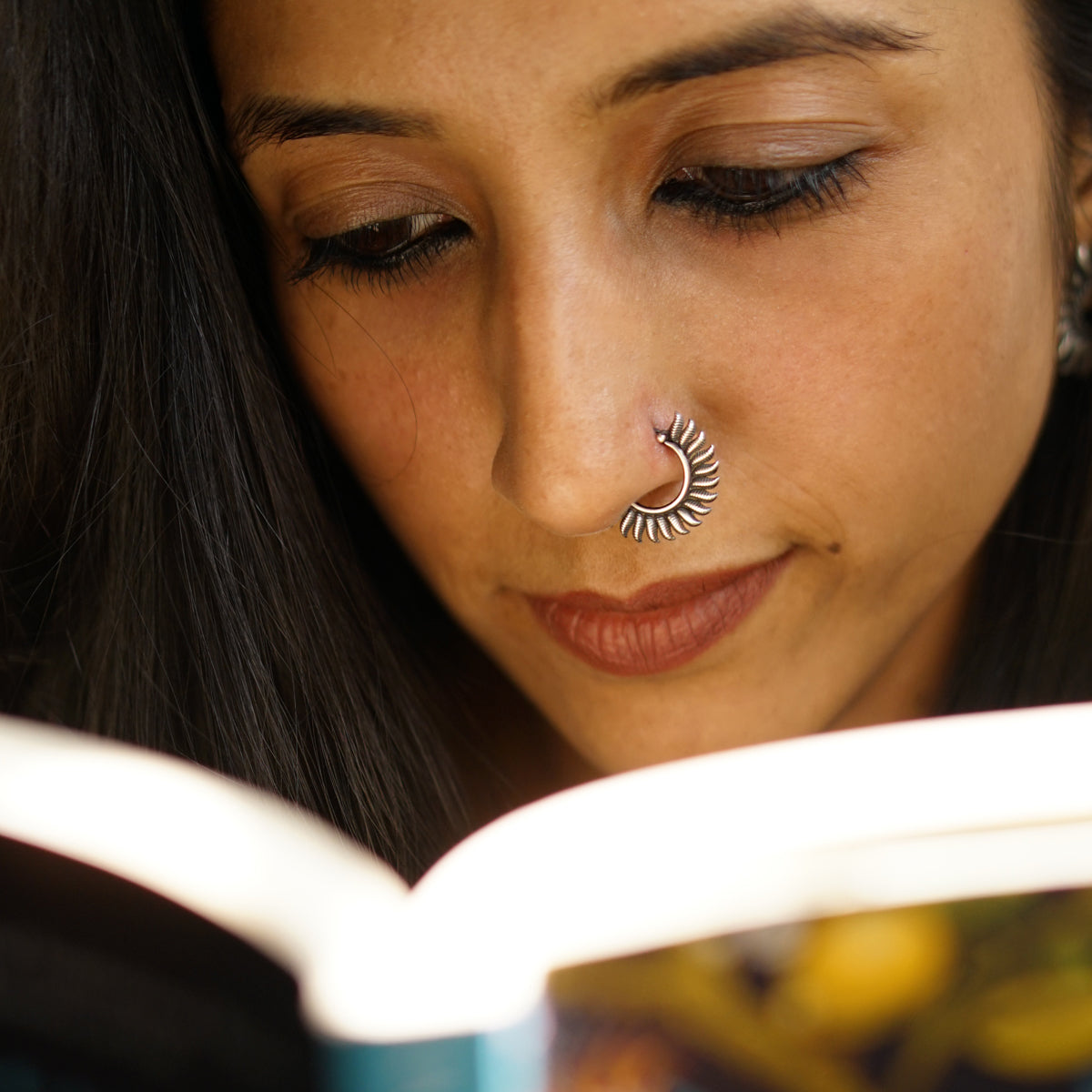 a woman with a nose piercing reading a book