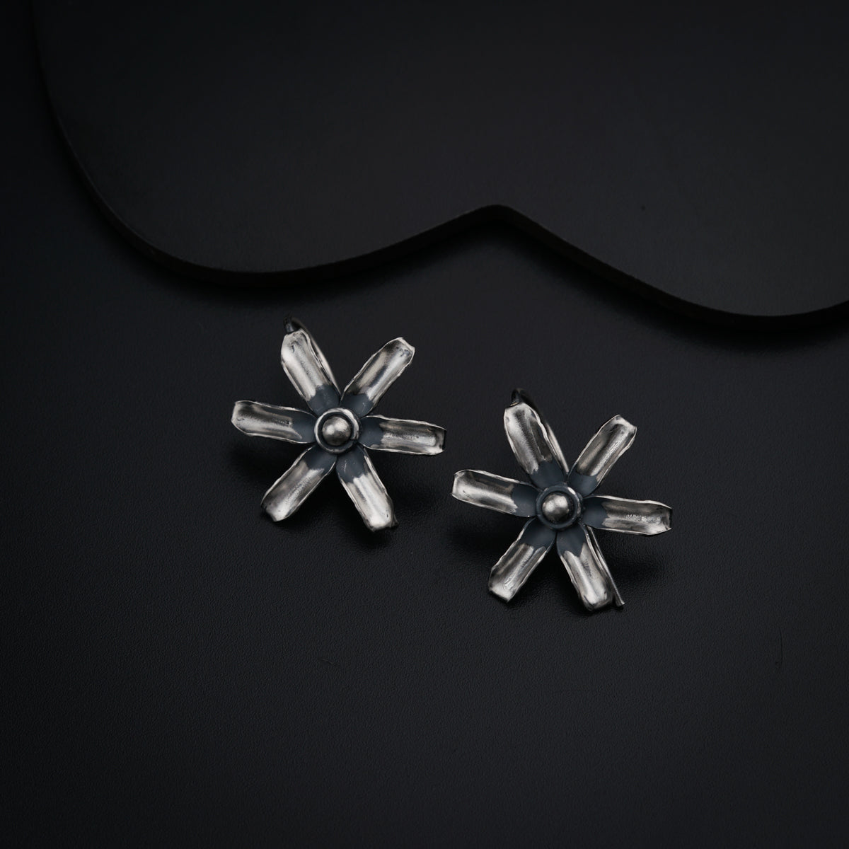 a pair of silver earrings on a black background