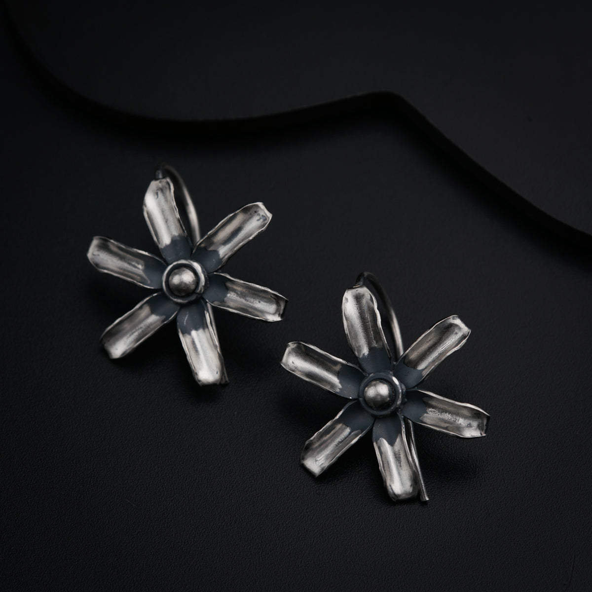 a pair of silver earrings on a black surface