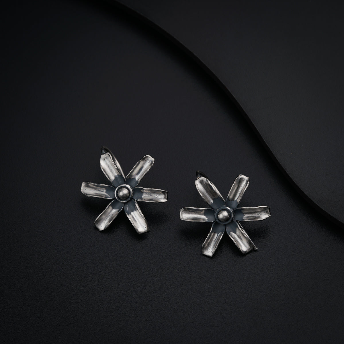 a pair of silver earrings on a black surface