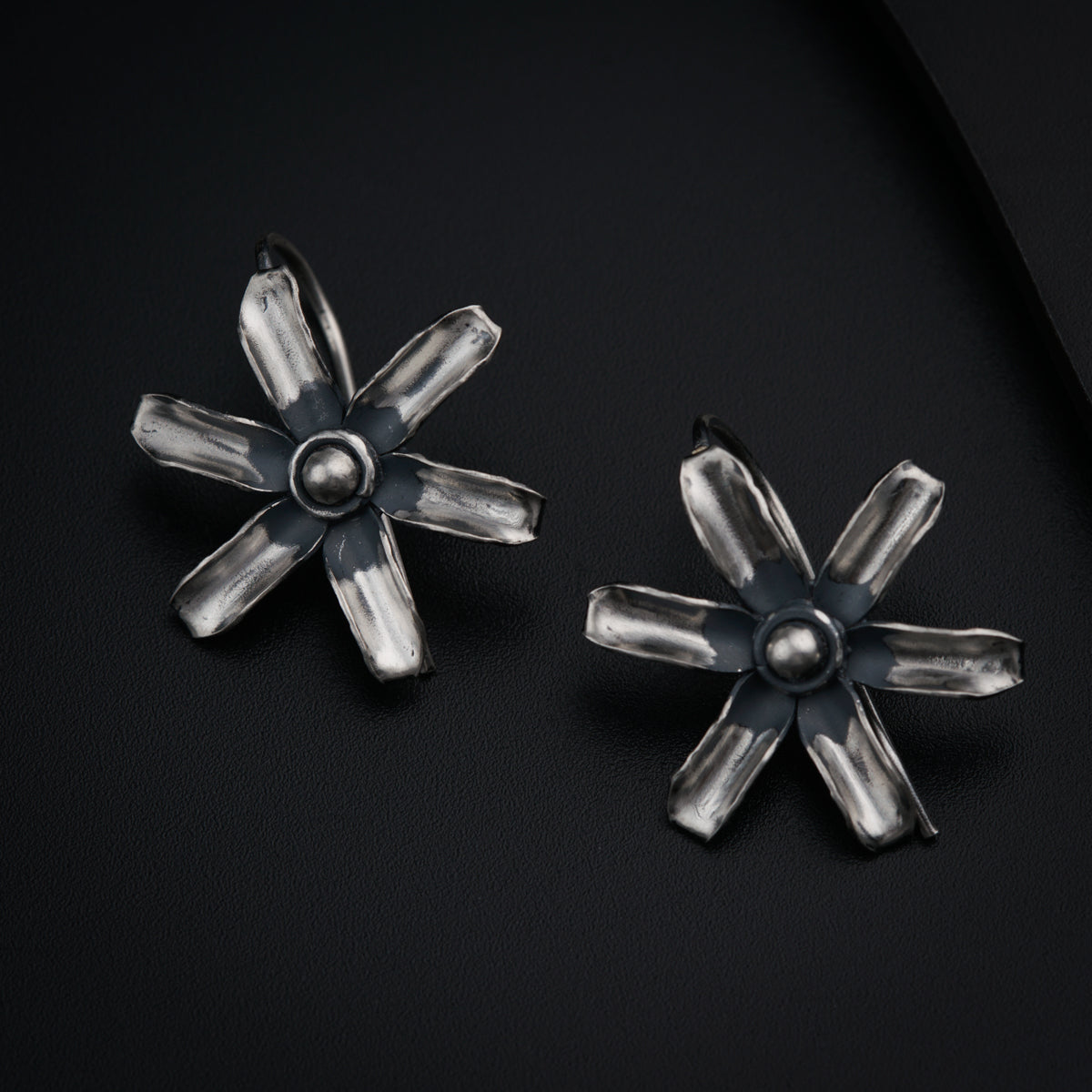 a pair of silver earrings on a black surface