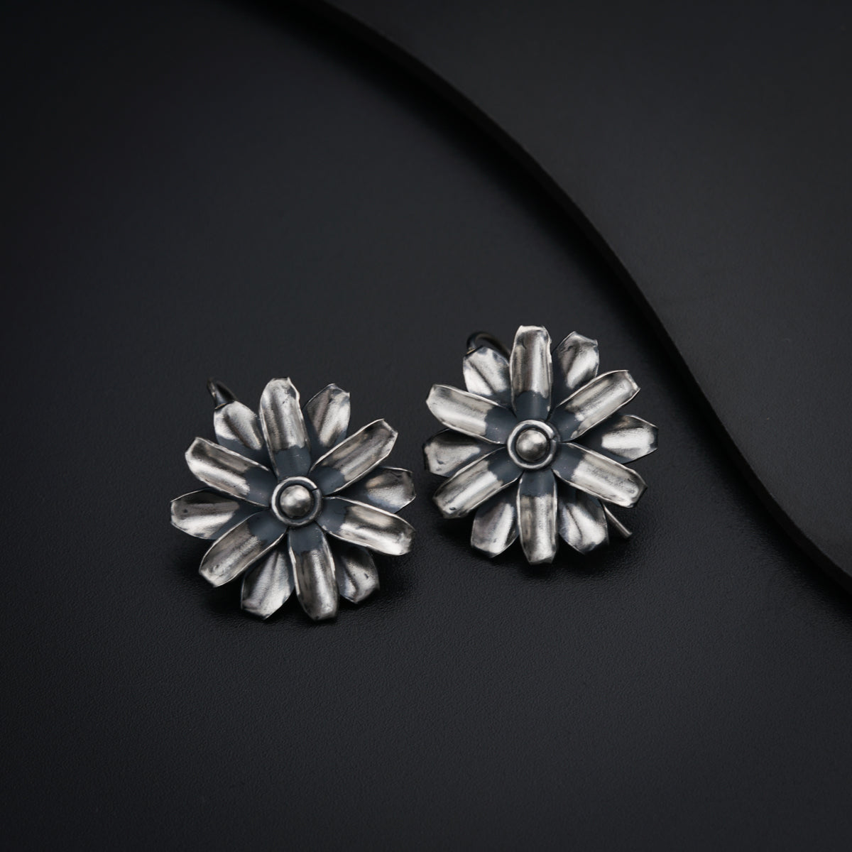 a pair of silver earrings sitting on top of a black surface