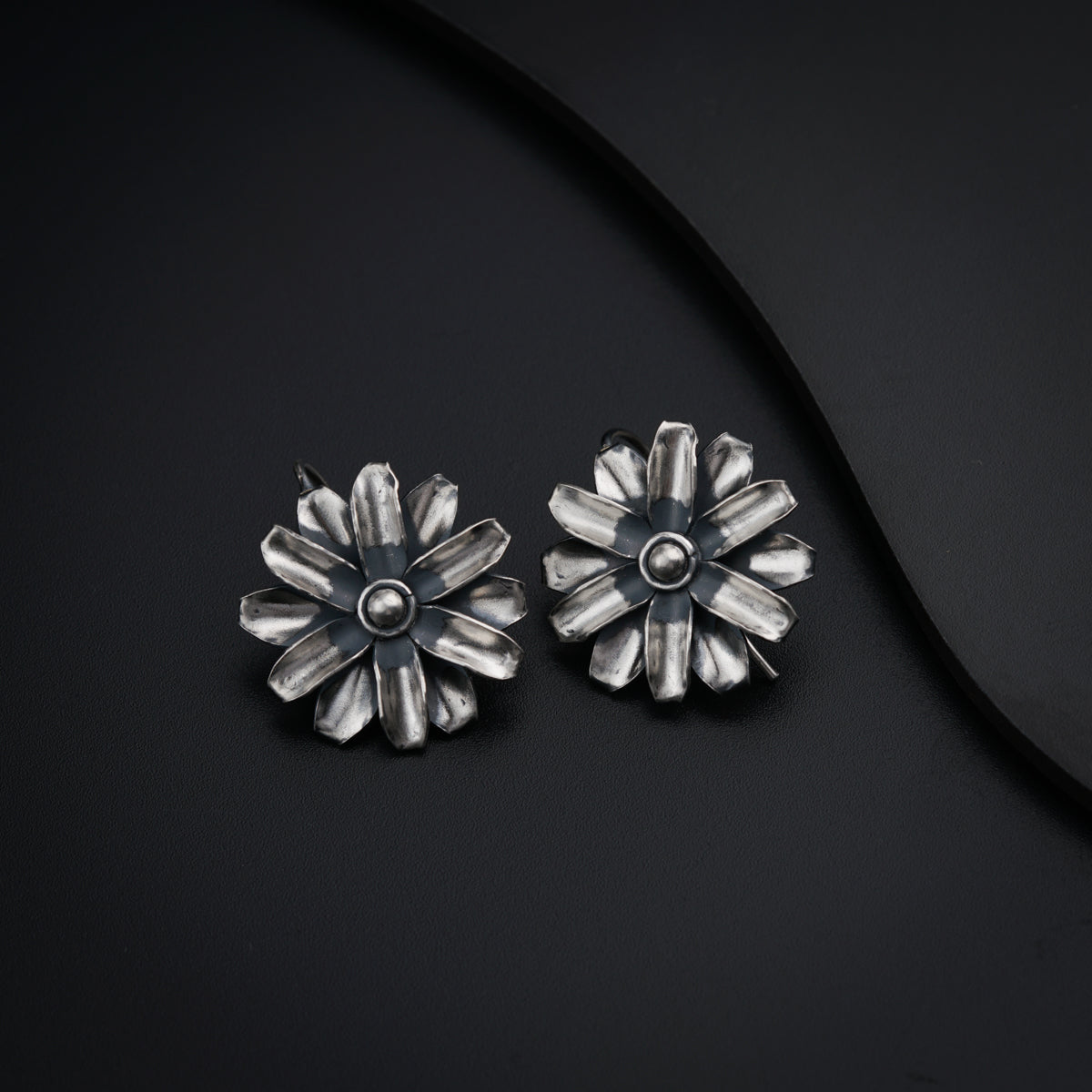 a pair of silver flower earrings on a black surface