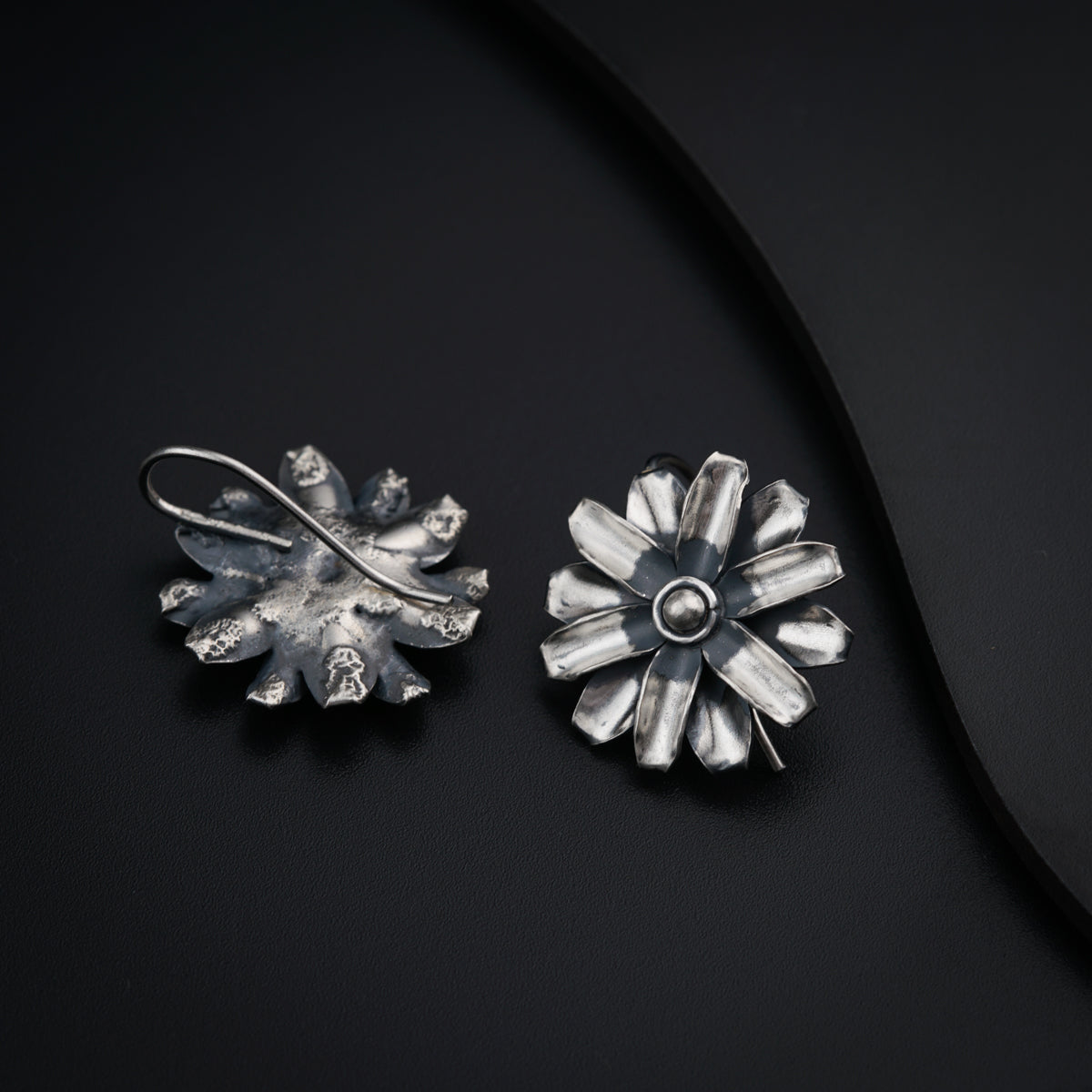 a pair of silver earrings sitting on top of a black surface