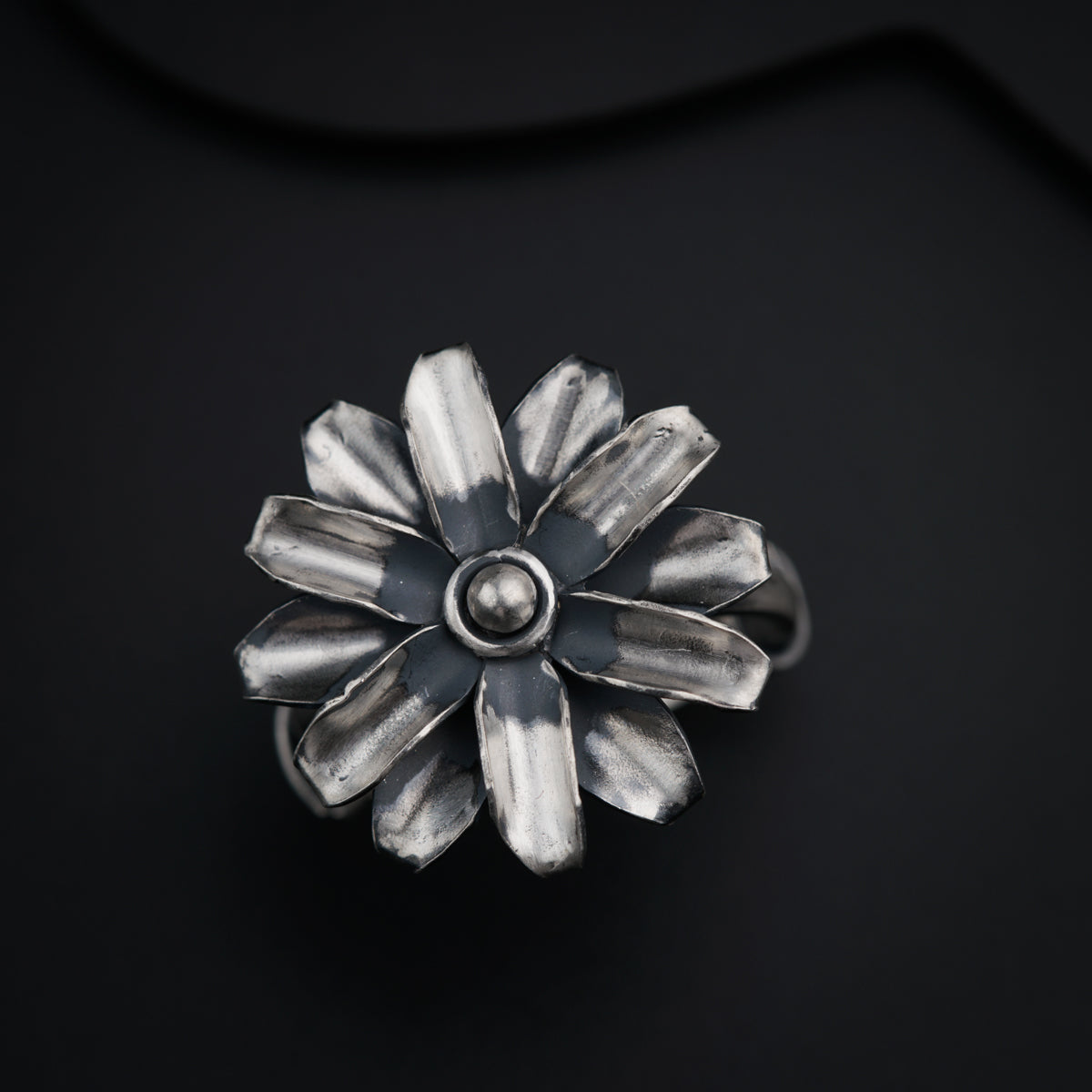 a silver flower ring on a black surface
