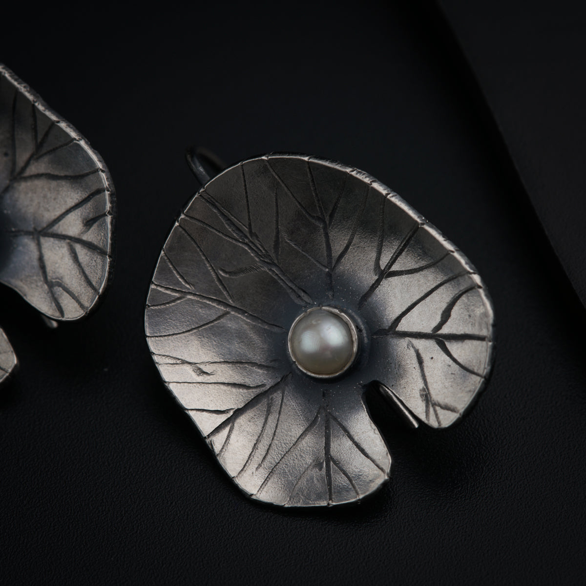 a pair of silver brooches with a pearl in the center