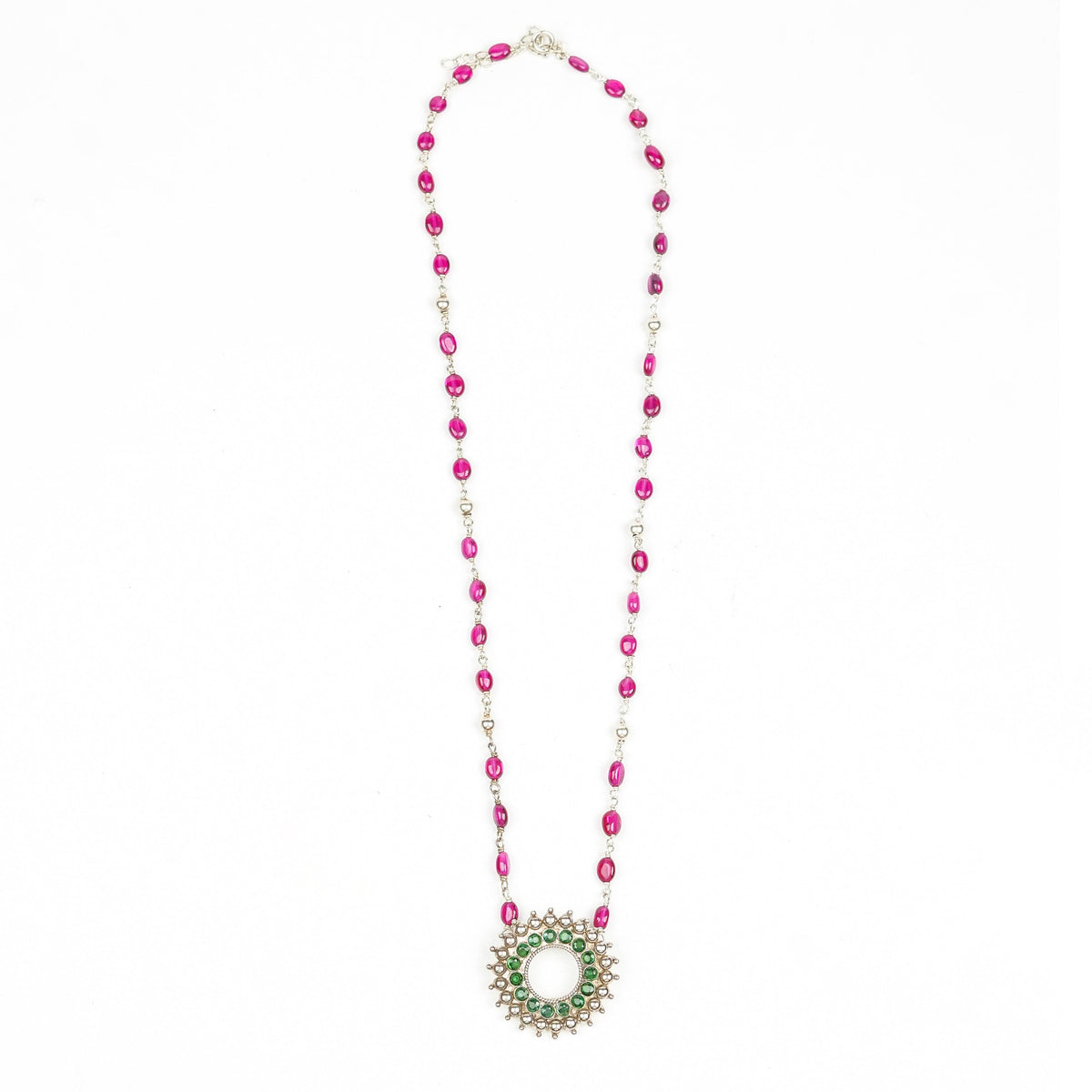 Flat-lay of a silver Karwar Motif Pendant & Ruby Ganthan Necklace with complementary silver jewellery and traditional accessories