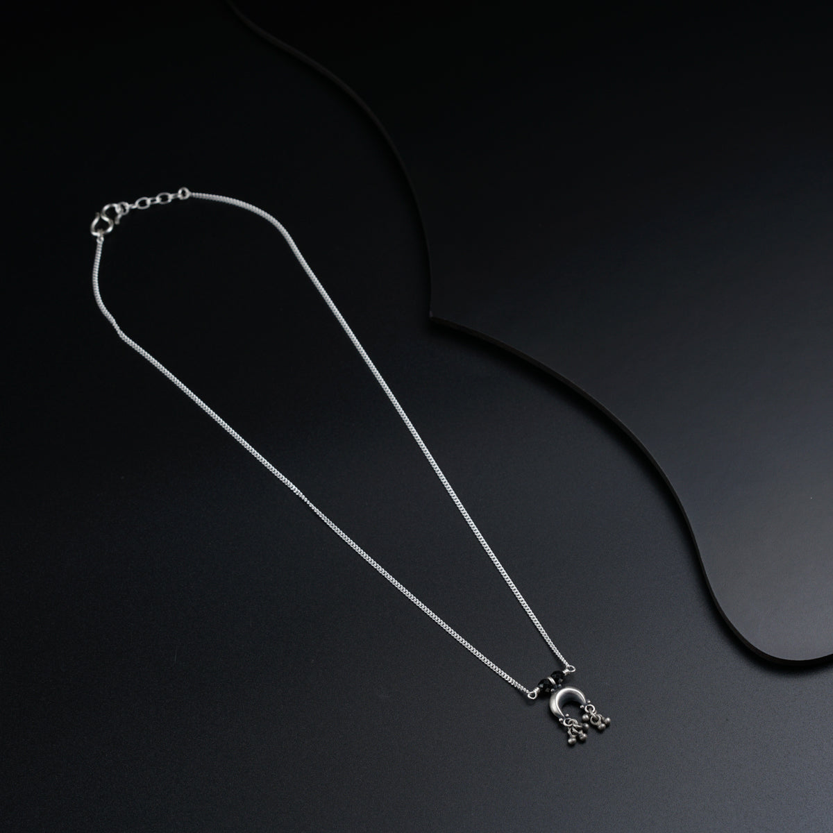 a black and white photo of a necklace on a black background