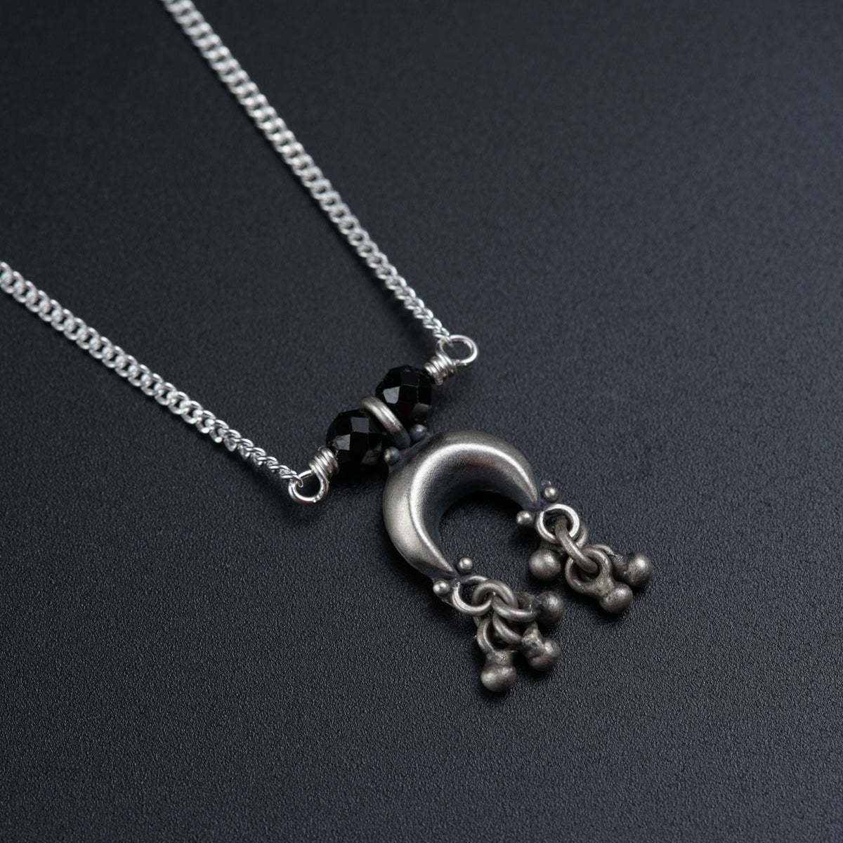 a silver necklace with a black bead hanging from it