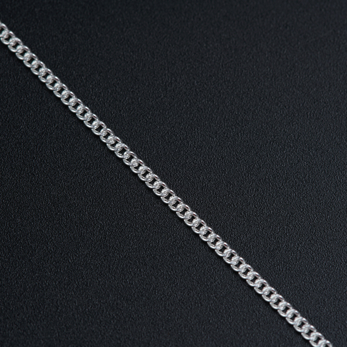 a silver chain on a black surface