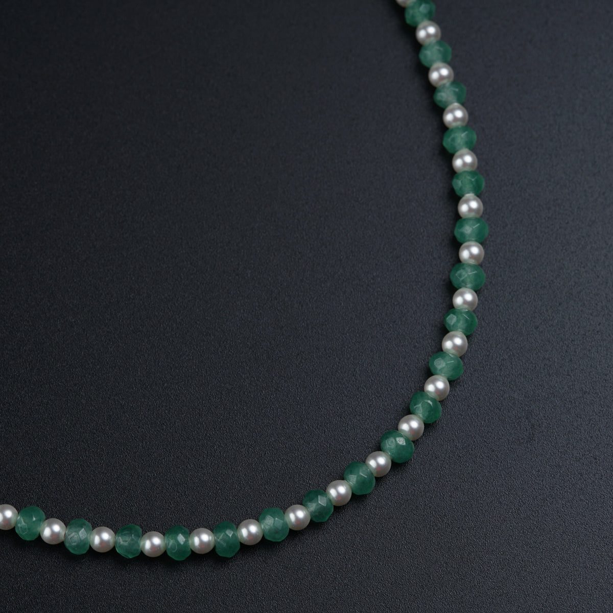 a beaded necklace with a green and white bead