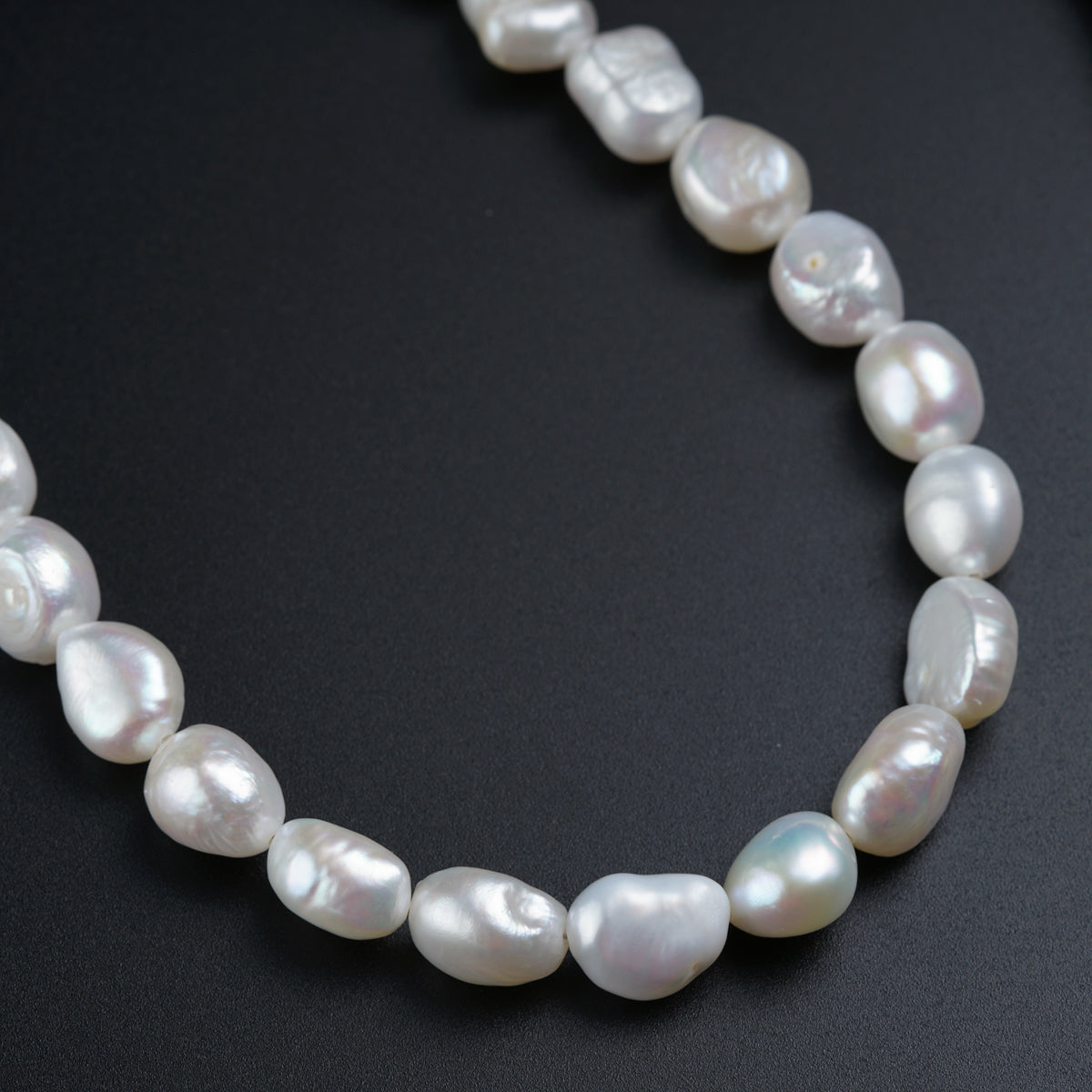 a necklace of white pearls on a black surface