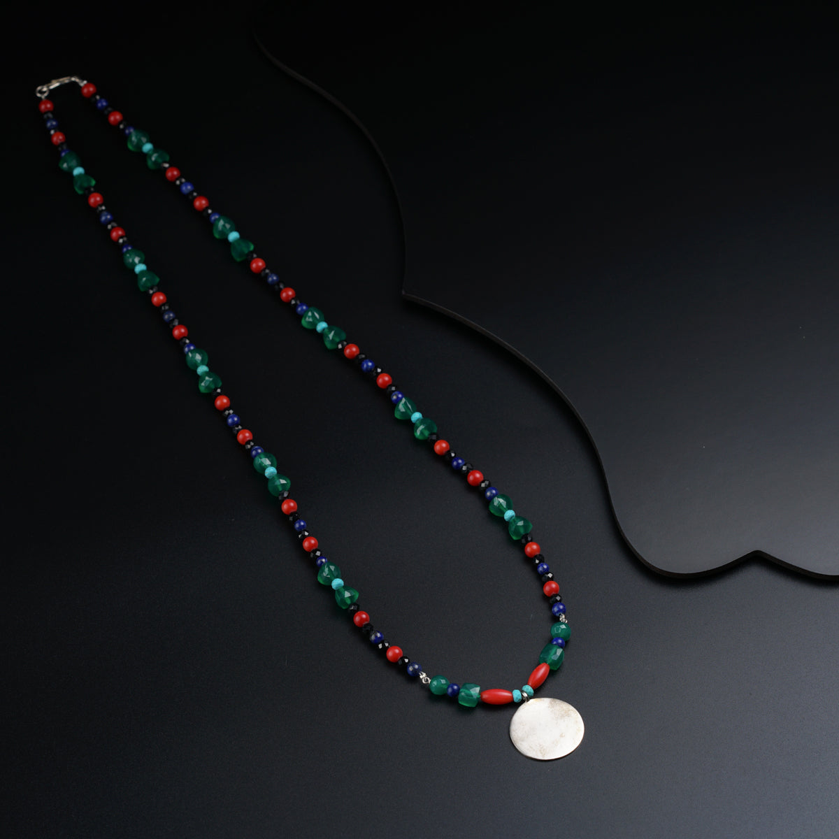 a necklace with a white disc on a black background